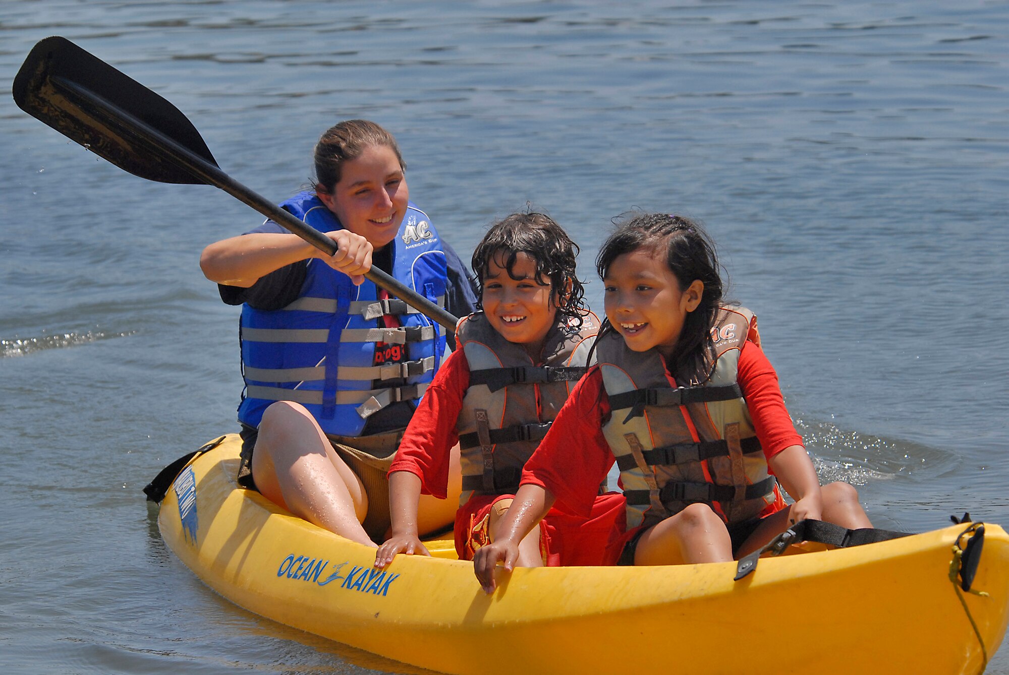 Three youth summer campers paddle a kayak on the Pacific Ocean. More than 38 children in the Youth Summer Camp Program spent the day kayaking, picnicking, and playing in the sand at Mothers’ Beach in Long Beach, Aug. 8.  (Photo by Joe Juarez)
