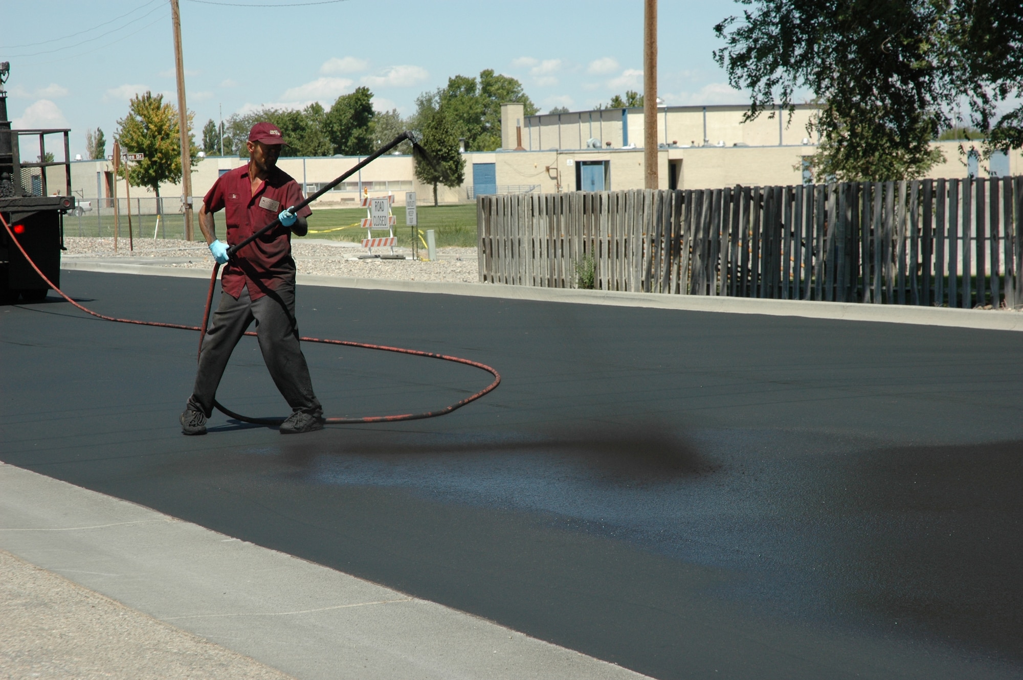 MOUNTAIN HOME AIR FORCE BASE, Idaho -- Del Cornish from the Curtis Clean Sweep asphalt maintenance company applies slurm sealant on Gunfighter Avenue near the Base Exchange to seal the street surface Aug. 10. Gunfighter Avenue from the base primary school to Alpine Street remains closed to traffic through Aug. 15 while contractors asphalt the spray-on seal coat to lengthen the pavement’s life. (U.S. Air Force photo/Master Sgt. Brian S. Orban)