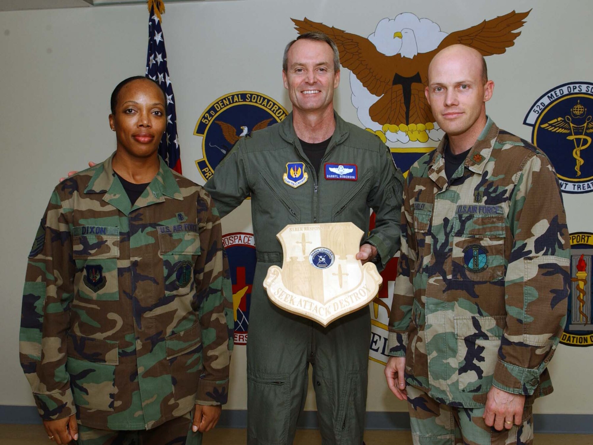 SPANGDAHLEM AIR BASE, Germany -- Col. Darryl Roberson, 52nd Fighter Wing commander, presents a Saber Responsible Choices plaque to Master Sgt. Deborah Dixon and Maj. Darren Shirley, both from the 52nd Medical Support Squadron, Aug. 9. The plaque with the coin in place symbolizes that the unit has gone more than 52 days with out a squadron member receiving a driving under the influence charge or an alcohol related incident. The medical group has gone more than two years without any ARIs or DUIs.  (US Air Force photo/Airman 1st Class Allen Pollard)   