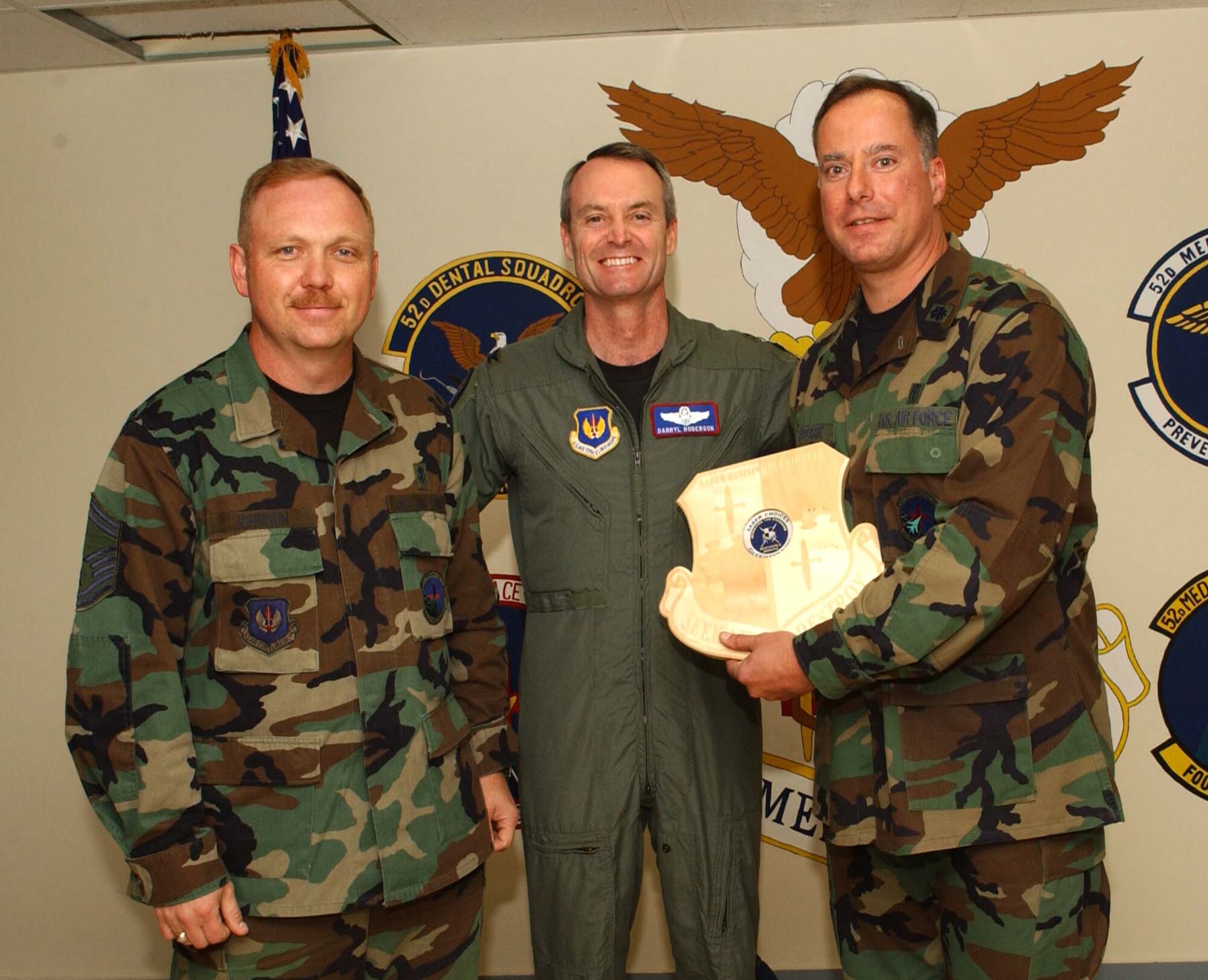 SPANGDAHLEM AIR BASE, Germany -- Col. Darryl Roberson, 52nd Fighter Wing commander, presents a Saber Responsible Choices plaque to Senior Master Sgt. Rick Johnson and Lt. Col. James Harcarik, both from the 52nd Aerospace Medicine Squadron, Aug. 9. The plaque with the coin in place symbolizes that the unit has gone more than 52 days with out a squadron member receiving a driving under the influence charge or an alcohol related incident. The medical group has gone more than two years without any ARIs or DUIs.  (US Air Force photo/Airman 1st Class Allen Pollard)   