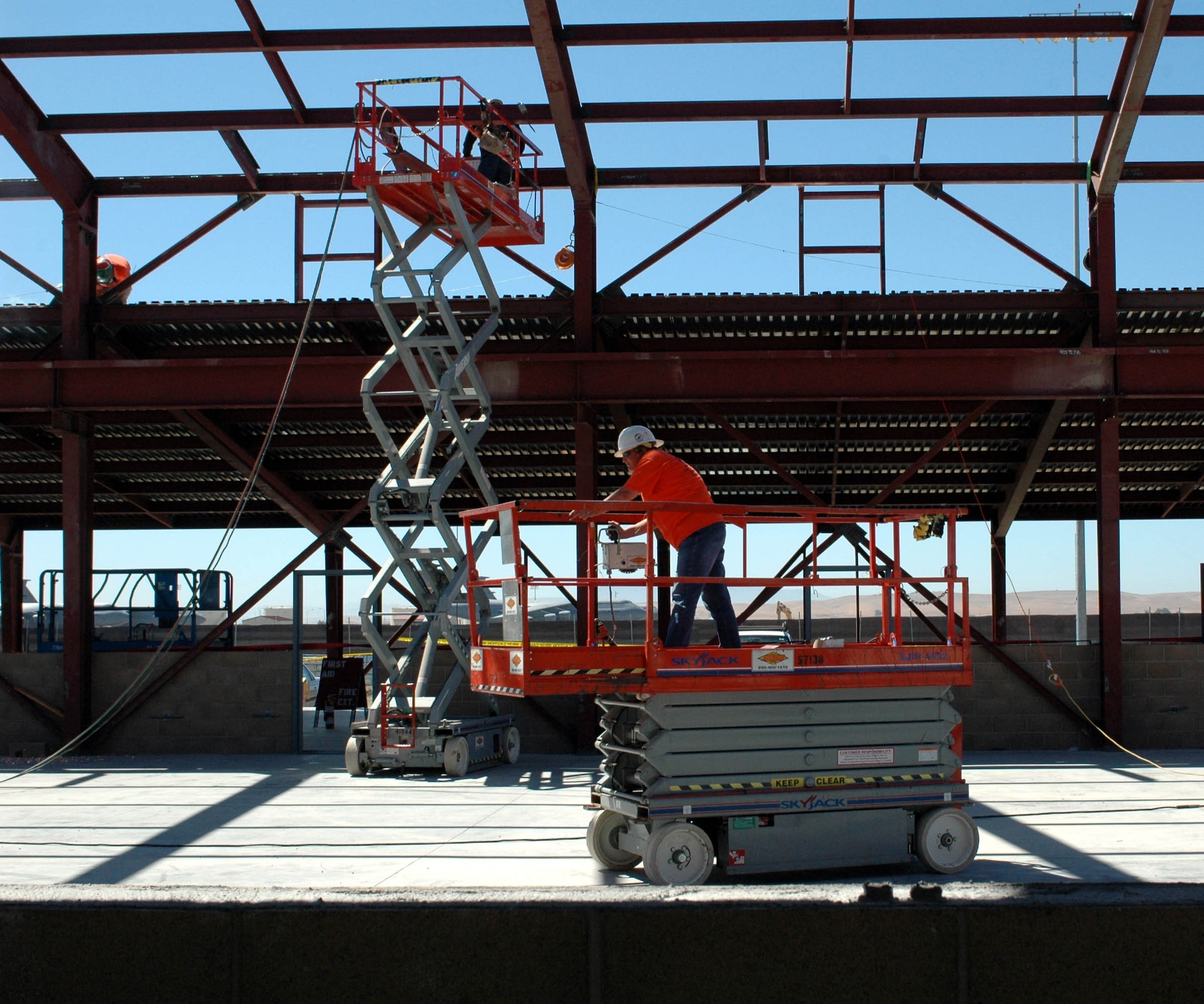 Scissor lifts push workers toward the ceiling so they can welded steel into place for the roof of the future Aerospace Ground Equipment building. (U.S. Air Force photo/ Nick DeCicco)