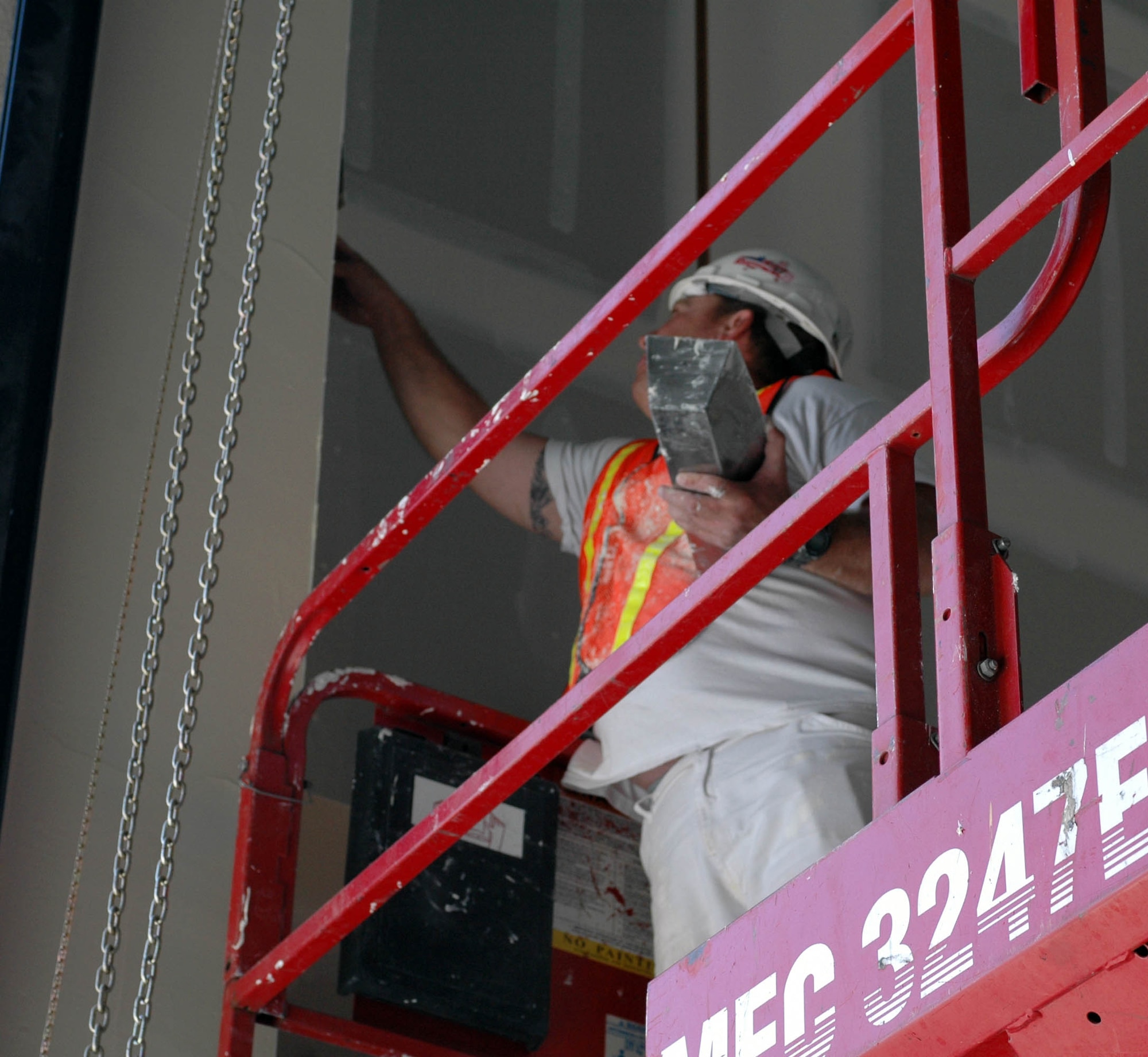 Aaron Lake puts tape in place in the new C-17 maintenance facility building. The tape is used to cover gaps or cuts in the drywall before painting. (U.S. Air Force photo/ Nick DeCicco)