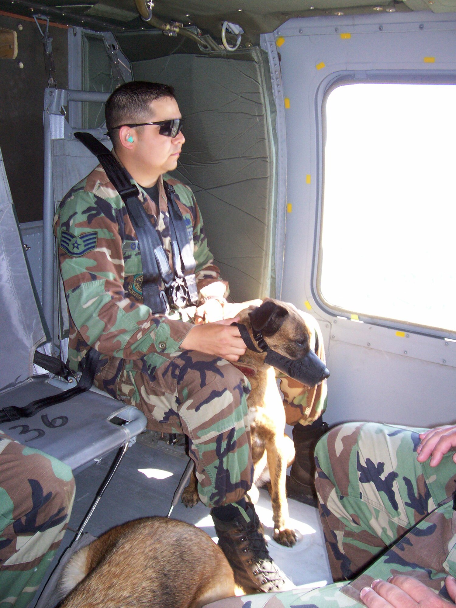 Staff Sgt. Mark Ochoa sits with his military working dog, Borek, during a Blackhawk flight.  The handlers and their dogs were students in the U.S. Air Force Expeditionary Center's Phoenix Warrior Course at Fort Dix, N.J.  The flight in the helicopter helped condition the dogs to boarding and flying in a helicopter before they had to do that while deployed to Southwest Asia.  Sergeant Ochoa is a security forces Airman with the 319th Security Forces Squadron at Grand Forks Air Force Base, N.D.  (U.S. Air Force photo/Tech. Sgt. Jeffrey Dean)