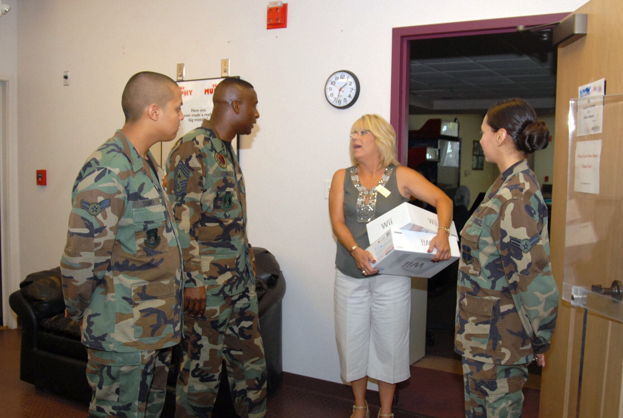 Chief Master Sgt. Juan Lewis (second from left), 95th Air Base Wing command chief, talks to Terry Stegman (third from left), Oasis Community Center director, as Airman 1st Class Isaiah Suarez (left), 95th Security Forces Squadron entry controller, and Airman 1st Class Melissa Lugo-Velez (right), 95th ABW Judge Advocate paralegal, look on at the Oasis on Aug. 10 during one of the stopovers for the Shadow Program. Airman Suarez was the honorary command chief as part of the Shadow Program implemented by Chief Lewis. The chief and the two Airmen donated video game consoles to the Oasis. (Photo by Airman 1st Class Julius Delos Reyes)
