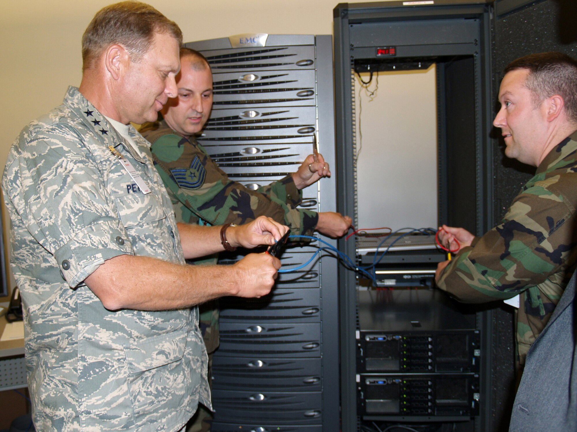 As part of a demonstration at the Global Cyberspace Integration Center, Lt. Gen. Michael W. Peterson, Tech. Sgt. Rob Eubank and Maj. Lanny Greenbaum clip wires to create a "network outage" to showcase server virtualization survivability.  General Peterson is Air Force chief of warfighting integration and chief information officer.  Major Greenbaum and Sergeant Eubank are with the GCIC modernization and innovation division.  (U.S. Air Force photo/Amelia Donnell)