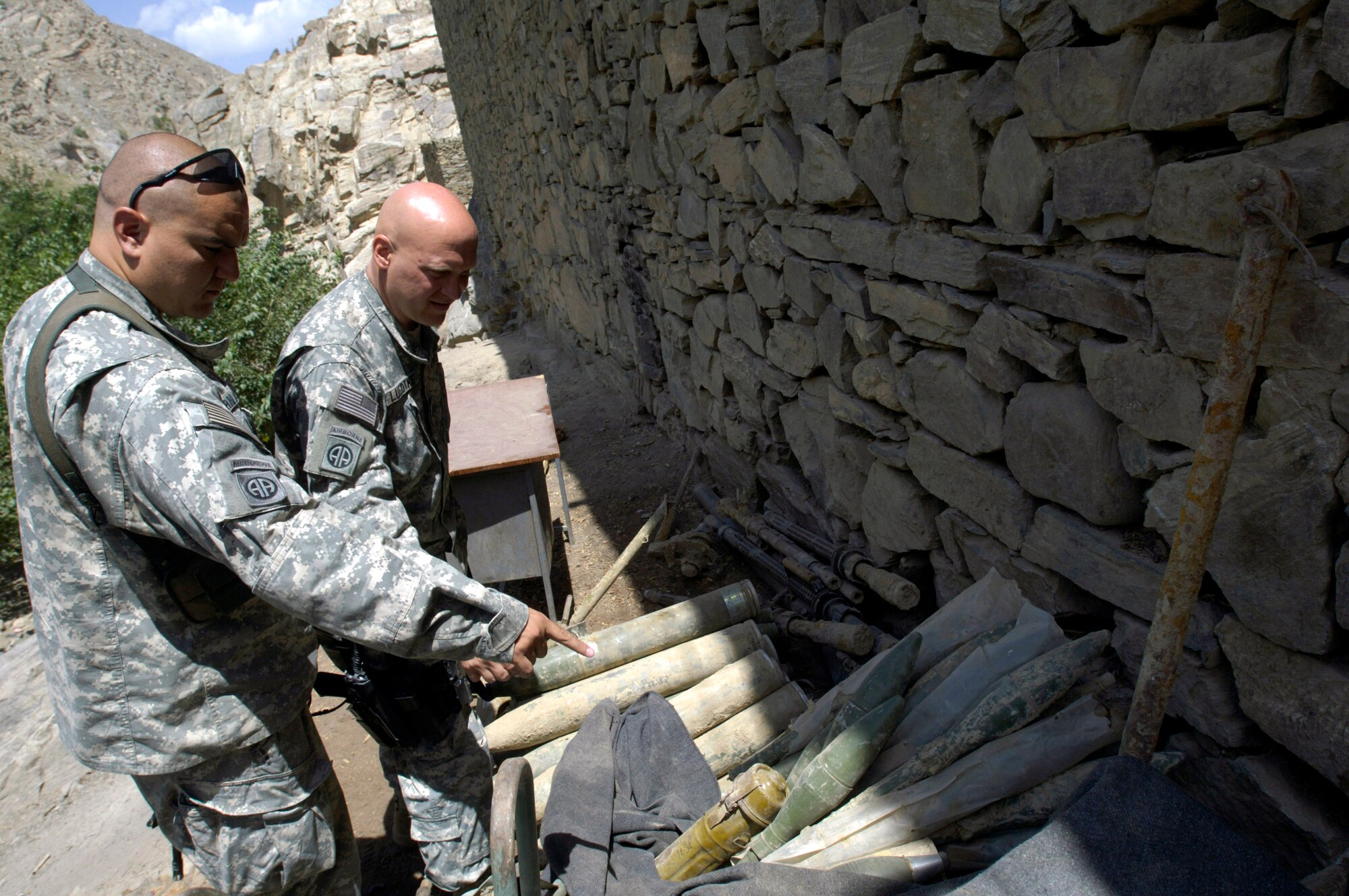 Panjshir Provincial Reconstruction Team commander Lt. Col. Christopher Luedtke (right) looks over a weapons cache Aug. 5 with Army Capt. Marco Hernandez.  The cache was uncovered after recent flooding in the province's Dara district on the site of a medical center expansion project.  Colonel Luedtke reported the find to the local Afghan National Police chief who safely disposed of the weapons.  (U.S. Air Force photo/Master Sgt. Jim Varhegyi)