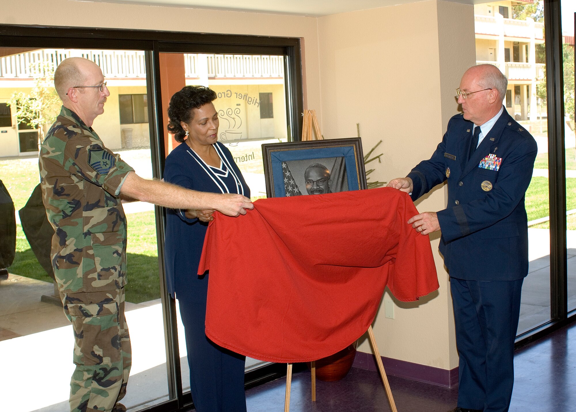 From left: Master Sgt. Shawn Aldridge, 95th Air Base Wing superintendent, Gwendolyn Reed, Chaplain (Lt. Col.) Herrie Reed's widow, and Chaplain (Brig. Gen.) Cecil Richardson, Air Force deputy chief of chaplains, unveil a portrait of Chaplain Reed on Aug. 10 during a ceremony dedicating the Higher Grounds Internet Cafe to the fallen chaplain. Chaplain Reed was the installation chaplain before he passed away from a stroke Sept. 22, 2006. (Photo by Jim Shryne) 