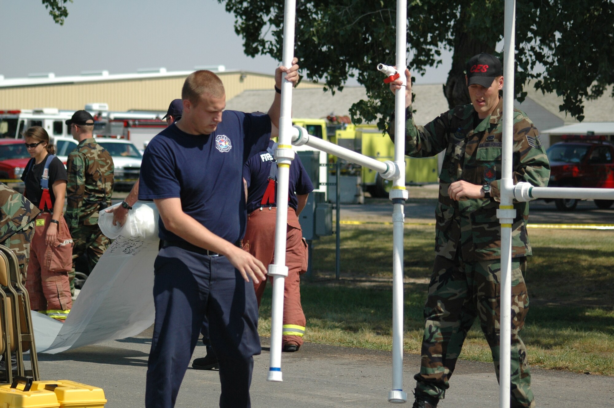 Staff Sgt. Adam Tisher, 341st Civil Engineer Squadron fire figther, helps a member of the Great Falls fire department set up decontamination stations during Operation Great Falls, a joint, off-base emergecny response exercise. The 341st CES is part of the regional hazardous materials assessment team. (U.S. Air Force photo / Airman 1st Class Emerald Ralston)
