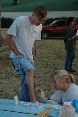 Tech. Sgt. Sarah Edwards, 341st Medical Operations Squadron, applies moulage to Airman 1st Class Michael Frank, 40th Heliciopter Squadron and role-player in the exercise, to create the appearance of wounds to be assessed by the paramedic team during Operation Great Falls, a joint, off-base emergency response exercise held at the Montana Expo Park Aug. 9. (U.S. Air Force photo / Airman 1st Class Emerald Ralston)