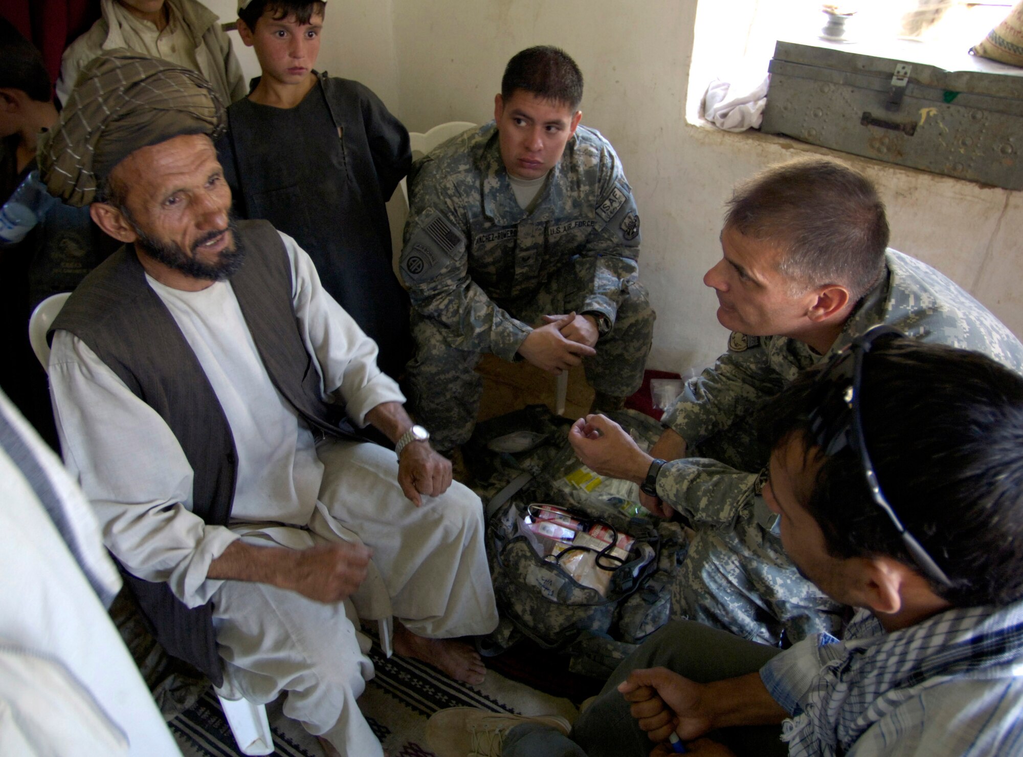 Panjshir Provincial Reconstruction Team members Capt. Kevin Kubly (second from right) and Staff Sgt. Andre Sanchez-Romero listen as a villager explains his health-related concerns to them through an interpreter Aug. 7 in Roydara village in the Shutol district of Panjshir province, Afghanistan. Captain Kubly is a physician's assistant deployed from the 3rd Medical Group at Elmendorf Air Force Base, Alaska. Sergeant Sanchez-Romero is a security forces member deployed from Minot AFB, N.D. They and their fellow PRT members made an 11-mile round-trip trek over a mountain pass and into a river valley to provide medical care to Afghans living in Roydara. (U.S. Air Force photo/Master Sgt. Jim Varhegyi)
