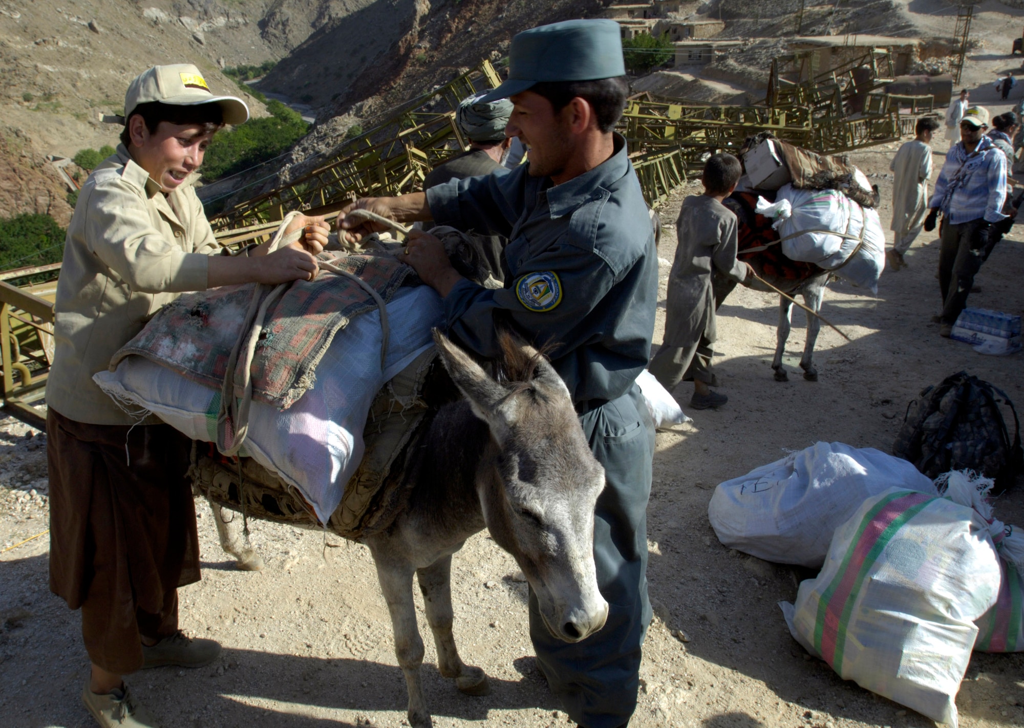 A village boy and a member of the Afghan National Police load a donkey with medical supplies and humanitarian aid for members of the Panjshir Provincial Reconstruction Team Aug. 7 in Afghanistan. The PRT members made an 11-mile round-trip trek over a mountain pass and into a river valley to provide medical care to Afghans living in Roydara village in the Shutol district of Panjshir province. (U.S. Air Force photo/Master Sgt. Jim Varhegyi)
