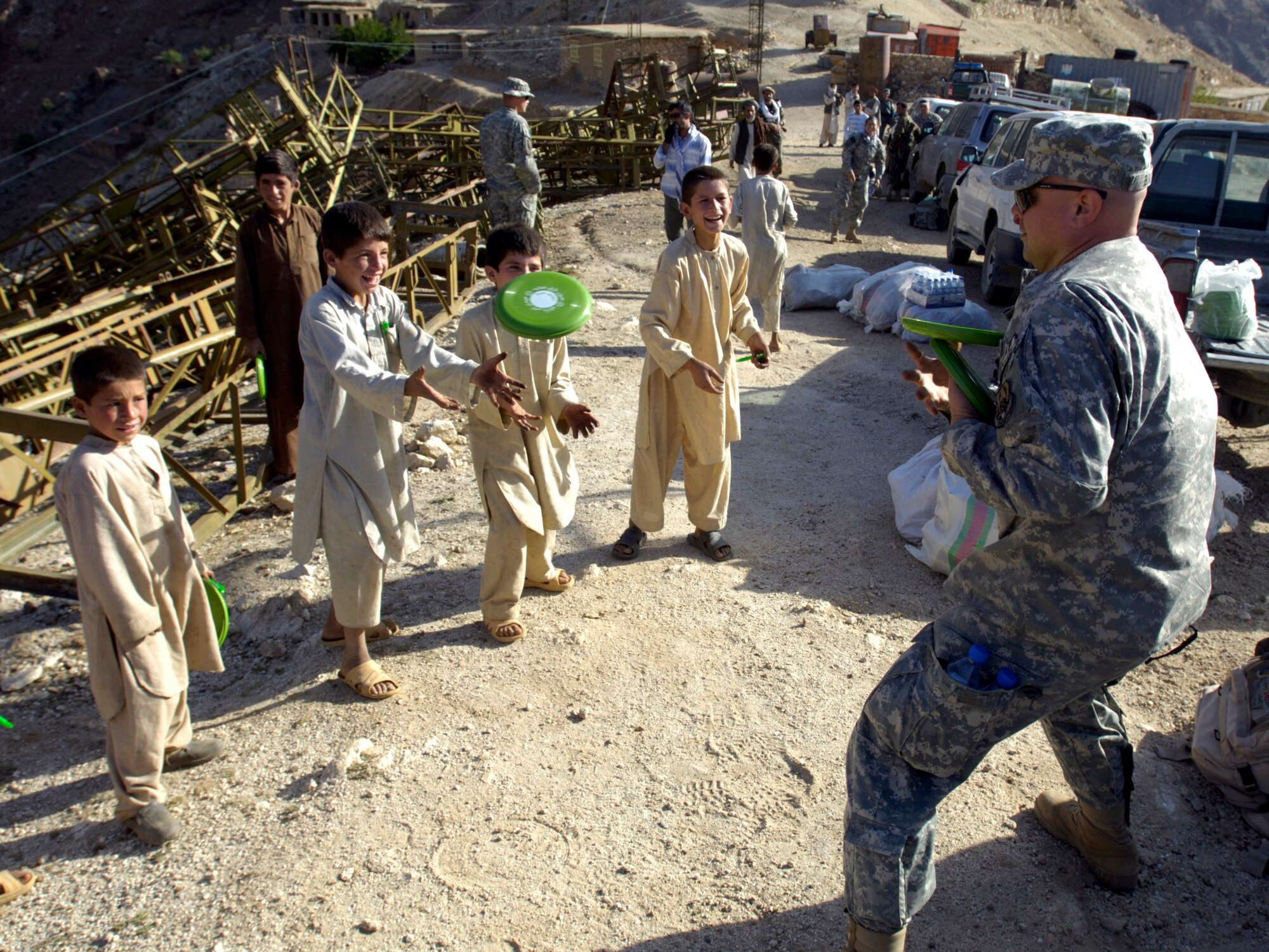 Tech. Sgt. Ralph Binion III plays with a flying disc with village boys Aug. 7 in Roydara village in the Shutol district of Panjshir province, Afghanistan. Sergeant Binion is a services craftsman deployed from Mountain Home Air Force Base, Idaho,and is a member of the Panjshir Provincial Reconstruction Team. He and his fellow PRT members made an 11-mile round-trip trek over a mountain pass and into a river valley to provide medical care to Afghans living in Roydara. (U.S. Air Force photo/Master Sgt. Jim Varhegyi)
