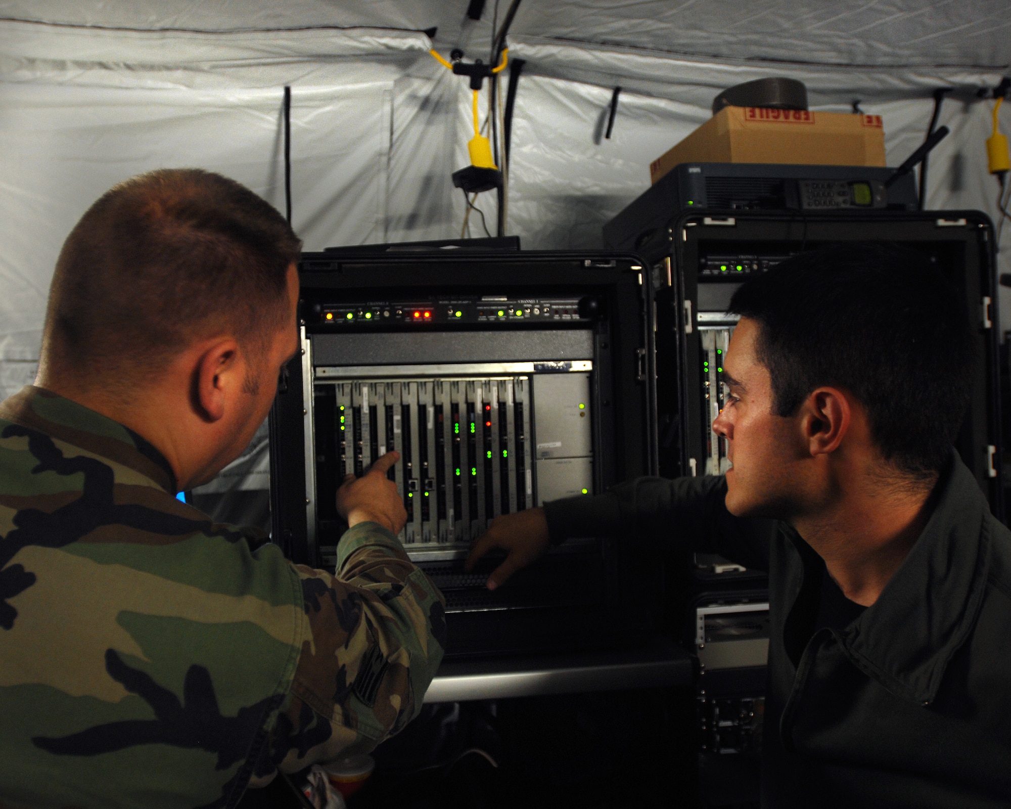 1st Combat Communications Squadron lead tech control technician, Staff Sgt. Andrew Wagner (left) and satelite communications technician Senior Airman Patrick Paez (right) ensure the effective distribution of secure/unclass voice and data services using their smart bandwidth at exercise Healthy Star.  Healthy Star's objective was to assist 3rd Air Force in developing a contingency plan for conducting humanitarian relief operations. (U.S. Air Force photo/Airman 1st Class Kenny Holston)