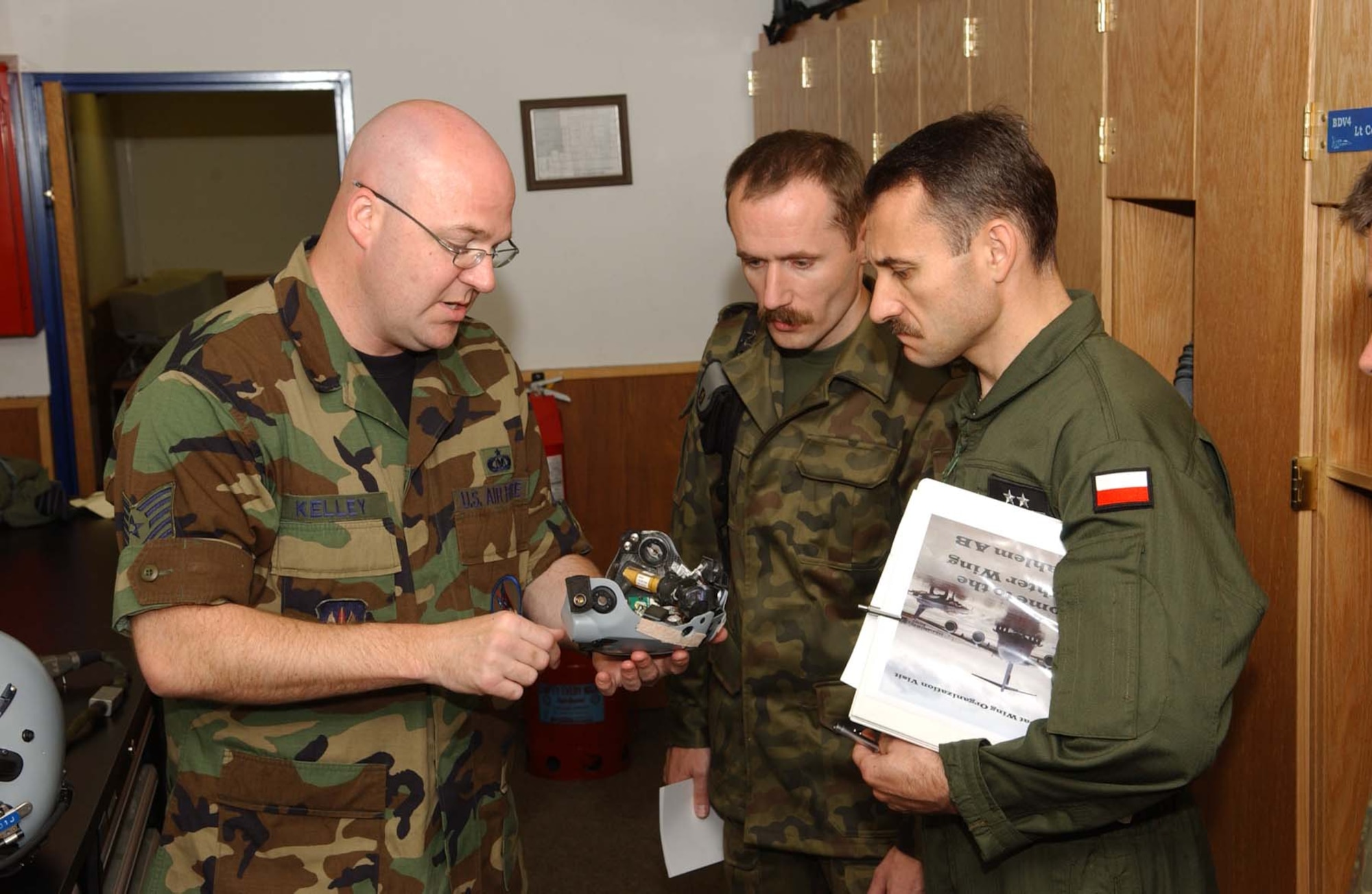 SPANGDAHLEM AIR BASE, Germany -- Tech. Sgt. Bull Kelley, 23rd Fighter Squadron, shows a helmet display unit from a Joint Helmet Mounted Cuing System at the 23rd FS Life Support section to Polish air force Maj. Krysztof Pusz and Col. Roscislaw Stepaniuk Aug. 7. Members of the Polish air force spent two days visiting Spangdahlem to learn about the base operations and support activities. (U.S. Air Force photo/Airman 1st Class Allen Pollard)
