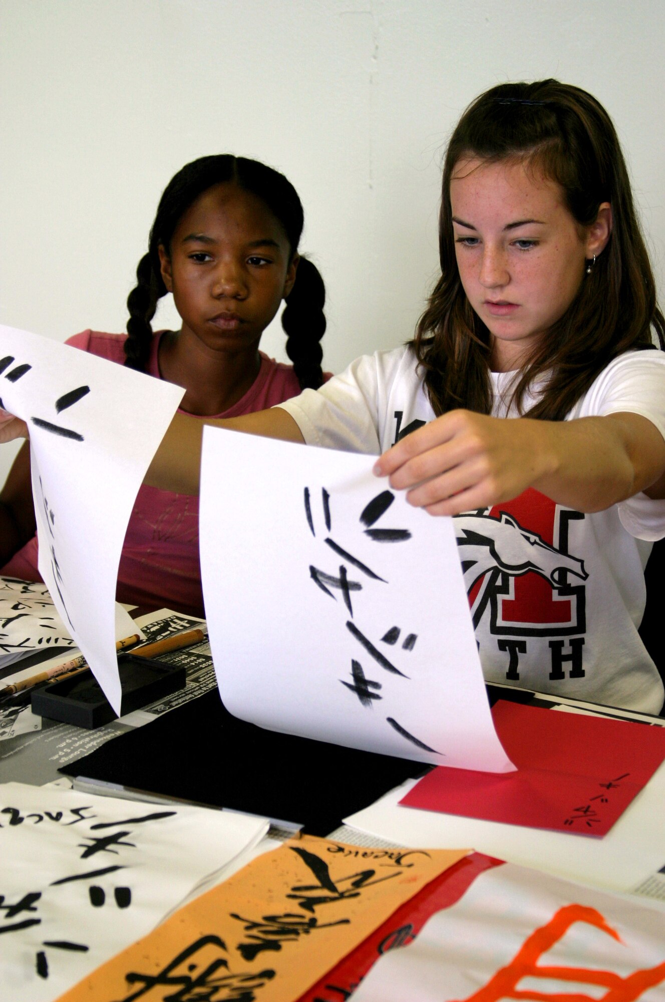 Jacque Entwistle (right) compares her calligraphy work with a template as friend Jazmine Lucas looks on during Japanese calligraphy class Aug. 10 at the Airman and Family Readiness Center. The cultural class series was an activity idea resulting from the teen town hall meeting in June.
(U.S. Air Force photo/Senior Airman Nestor Cruz)
