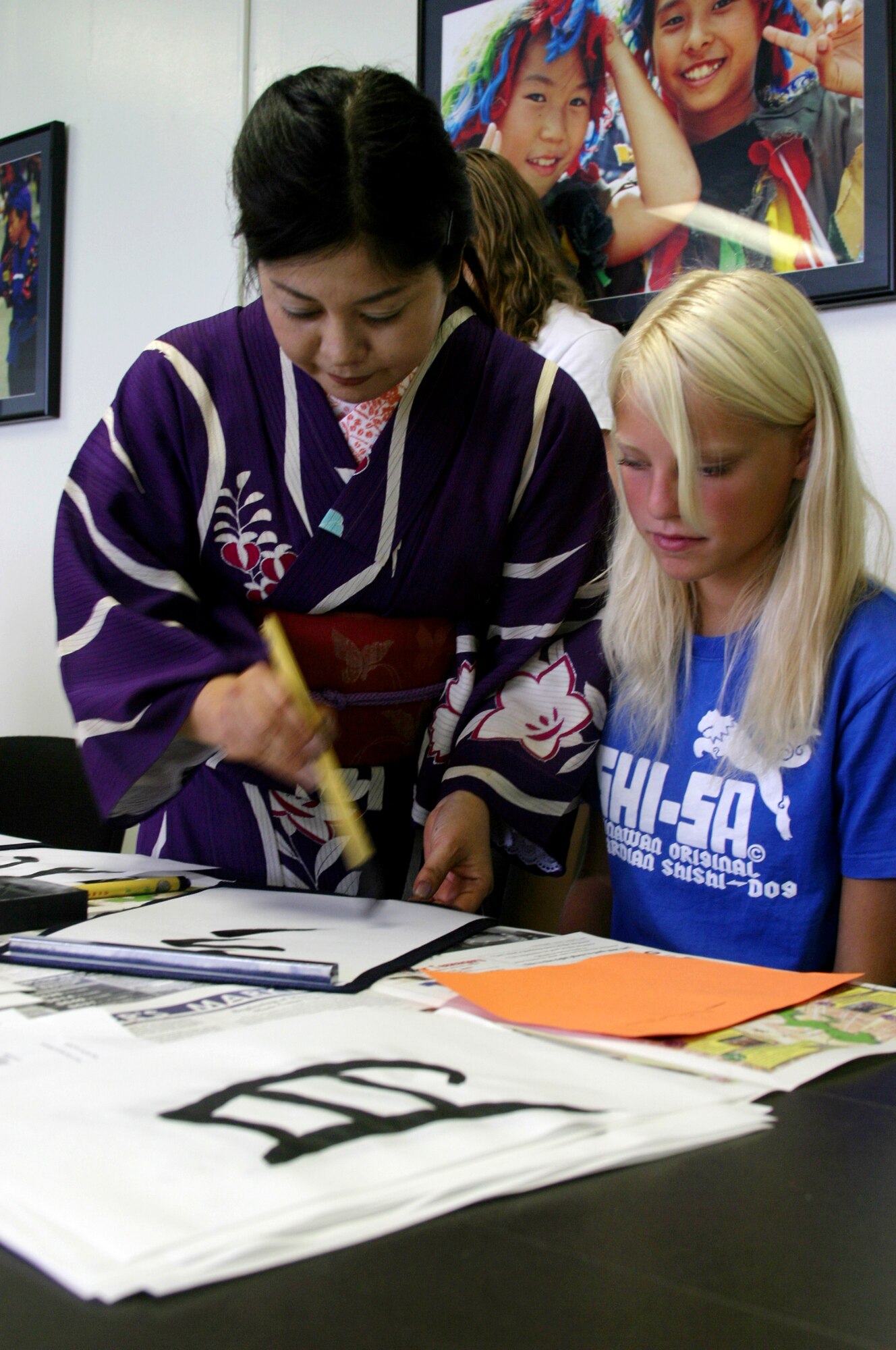 Kunii Takezaki, Japanese calligraphy master, shows Riley Witschen, daughter of Teresa Witschen, 18th Services Squadron youth center manager, how to perfect her calligraphy brush techniques Aug. 10 at the Airman and Family Readiness Center. The two-hour calligraphy class was the fifth in a series of free cultural classes designed to expose teens to various elements of Japanese culture. 
(U.S. Air Force photo/Senior Airman Nestor Cruz)
