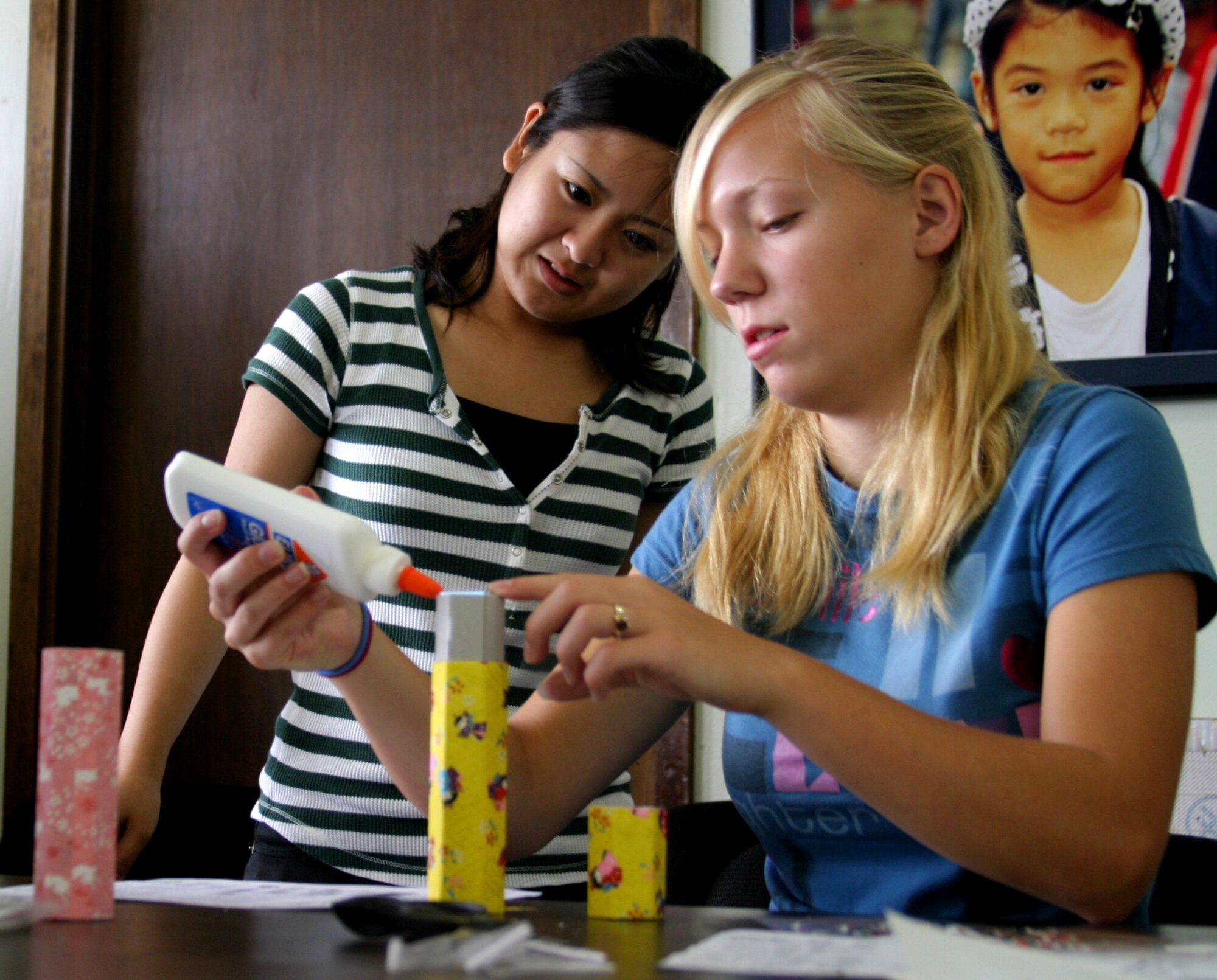 Shelby Witschen (right), daughter of Charles Witschen, Airman and Family Readiness Center community readiness consultant, works on her "mangekyoo" — a kaleidoscope decorated with Japanese paper called "washi" — as Sayaka Tanahara looks on during washi class Aug. 8 at the Airman and Family Readiness Center. The two-hour washi class was the third in a series of free cultural classes designed to expose teens to various elements of Japanese culture. 
(U.S. Air Force photo/Senior Airman Nestor Cruz)
