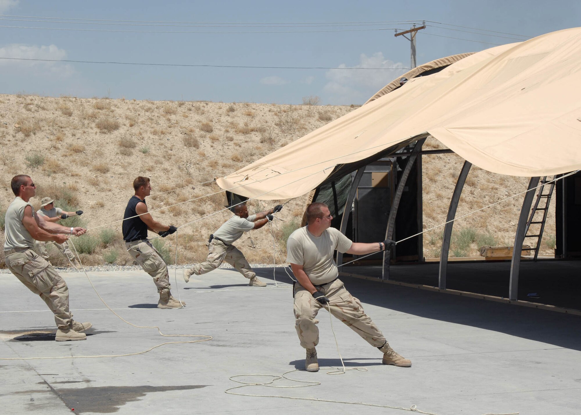 BAGRAM AIRFIELD, Afghanistan -- Members of the 455th Expeditionary Maintenance Squadron, work together to pull the exterior skin over the tent ribs during the build up of a California Tent for the ammunition troops at Bagram Airfield, Afghanistan. The maintainers worked alongside the 455th Expeditionary Civil Engineer Squadron to assist in the buildup of the tent. (U.S. Air Force photo by Senior Master Sgt. Kim Allain)