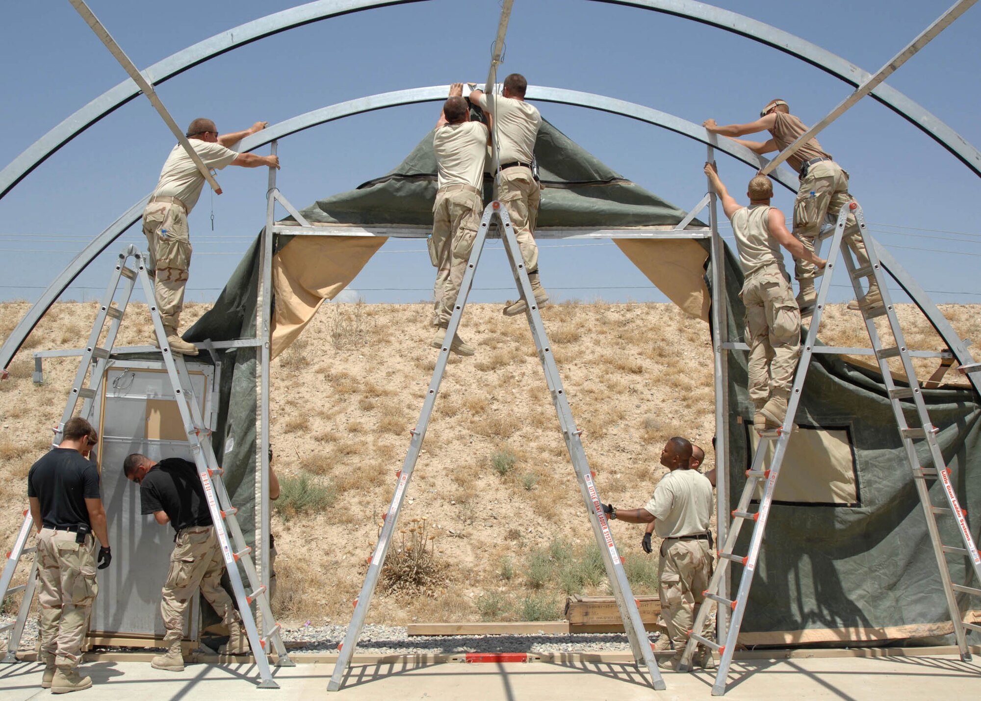 BAGRAM AIRFIELD, Afghanistan -- Members of the 455th Expeditionary Civil Engineer and Maintenance Squadrons, attach the support hooks of the back wall and door frame during the buildup of a California Tent for the ammunition troops at Bagram Airfield, Afghanistan. (U.S. Air Force photo by Senior Master Sgt. Kim Allain)