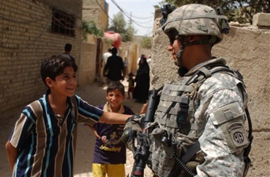 U.S. Army Staff Sgt. Antonio Alvarado jokes with two Iraqi boys during a patrol through the Adhamiyah district of Baghdad, Iraq, on Aug. 10, 2007.  Alvarado is attached to Bravo Battery, 2nd Battalion, 319th Airborne Field Artillery Regiment.  