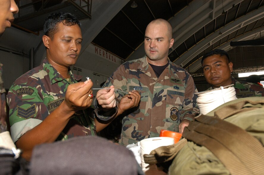 Staff Sgt. Christopher Keeter, a rigger from the Aerial Delivery Branch of the 353rd Operations Support Squadron, based at Kadena AB, Japan, gives members of the Indonesian Air Force a chance to take a closer look at different gauges of string used for tying bundles and parachutes for airdrops.  The exchange was part of Exercise Teak Iron, held at Halim and Bandung, Indonesia.
(U.S. Air Force photo/Master Sgt. Marilyn C. Holliday)
   