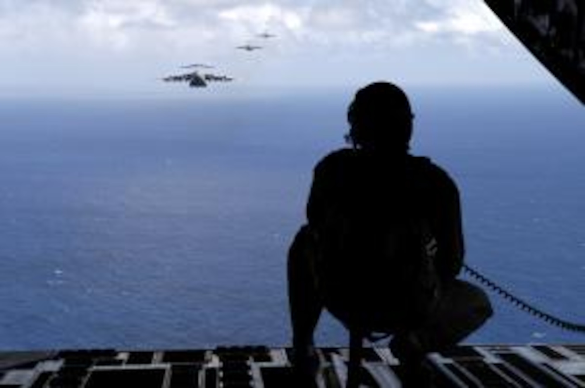 Senior Airman Todd Tichawa watches a formation of C-17 Globemaster III’s from the back of his aircraft Aug. 13, 2007 during a 4-ship airdrop training mission over the island of Oahu, Hawaii. SrA. Tichawa, a loadmaster with the 535th Airlift Squadron, Hickam Air Force Base, Hawaii is taking part in the training to maintain currency and proficiency. (U.S. Air Force photo by Tech. Sgt. Shane A. Cuomo)
