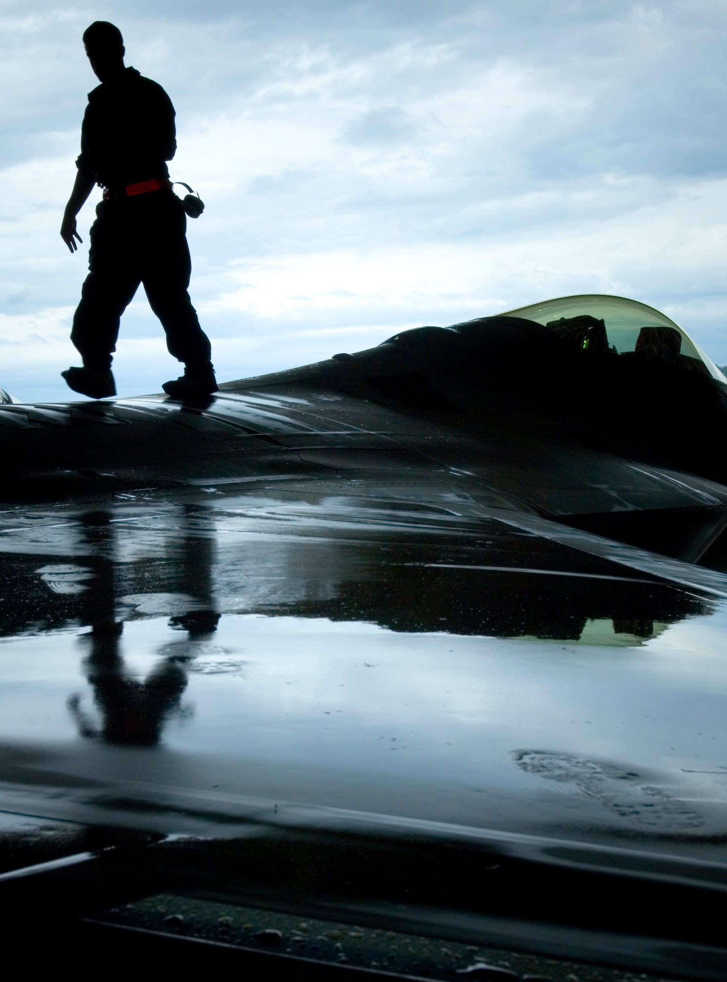 ELMENDORF AIR FORCE BASE, Alaska - Senior Airman Brandon Fontaine walks an F-22A Raptor wing removing tape used to prevent water from entering vents during washing. The 90th Fighter Squadron aircraft was detailed for the first time Aug. 14 since arriving here Aug. 8. Airman Fontaine is assigned to the 3rd Aircraft Maintenance Squadron, 90th Aircraft Maintenance Unit. (U.S. Air Force photo by Senior Garrett Hothan)