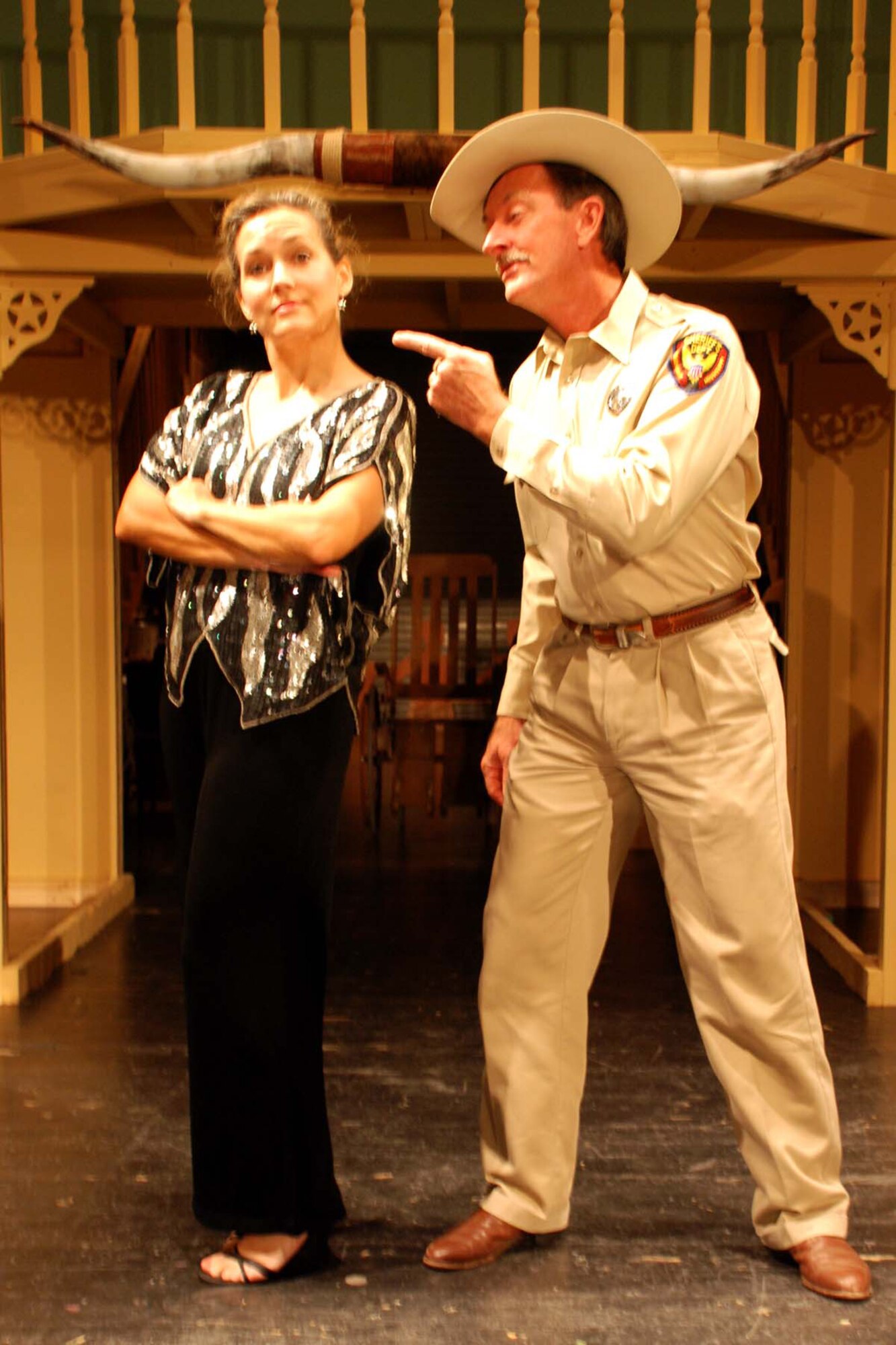 DEL RIO, Texas -- Sheriff Ed Earl Dodd, played by David Graf reminds proprietress Miss Mona, played by Kathryn McWilliams, what she’s selling at The Best Little Whorehouse in Texas.  The bawdy musical comedy is the latest Upstagers production and runs August 17, 18, 19, 24 and 25 at the Paul Poag Theatre.  Friday and Saturday performances are at 8pm, and the August 19 showing is at 2 p.m.  (U.S. Air Force photo)
