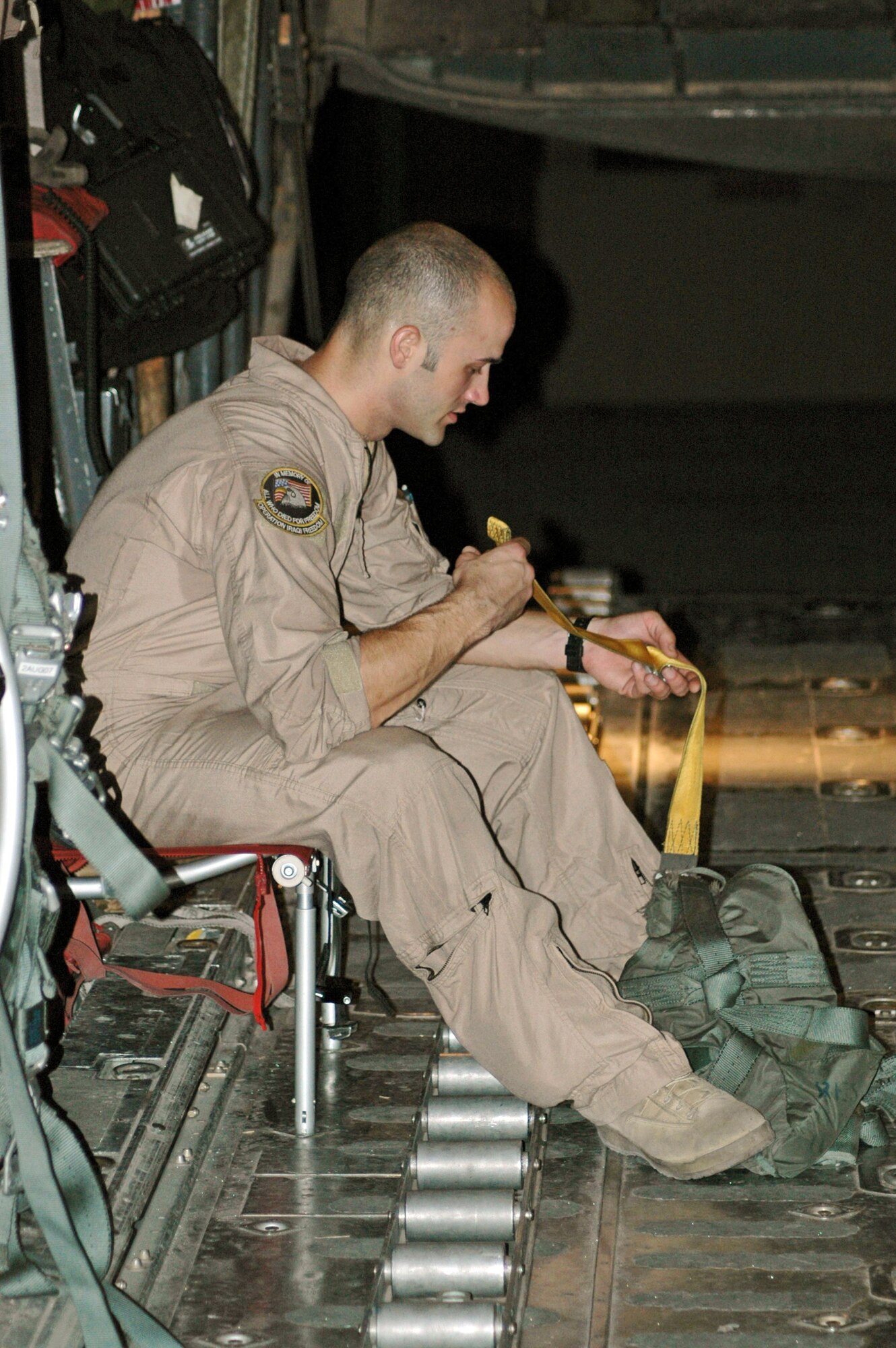 Staff Sgt. Tommy Greeness prepares his safety equipment prior to a low-level airdrop over Basra, Iraq.  The purpose of the airdrop was to spread leaflets over the battlefield below, sending a strong message to enemy insurgents discouraging acts of violence.  Sergeant Greeness is a C-130 Hercules loadmaster with the 746th Expeditionary Airlift Squadron.  U.S. Air Force photo/Capt. Teresa Sullivan) 