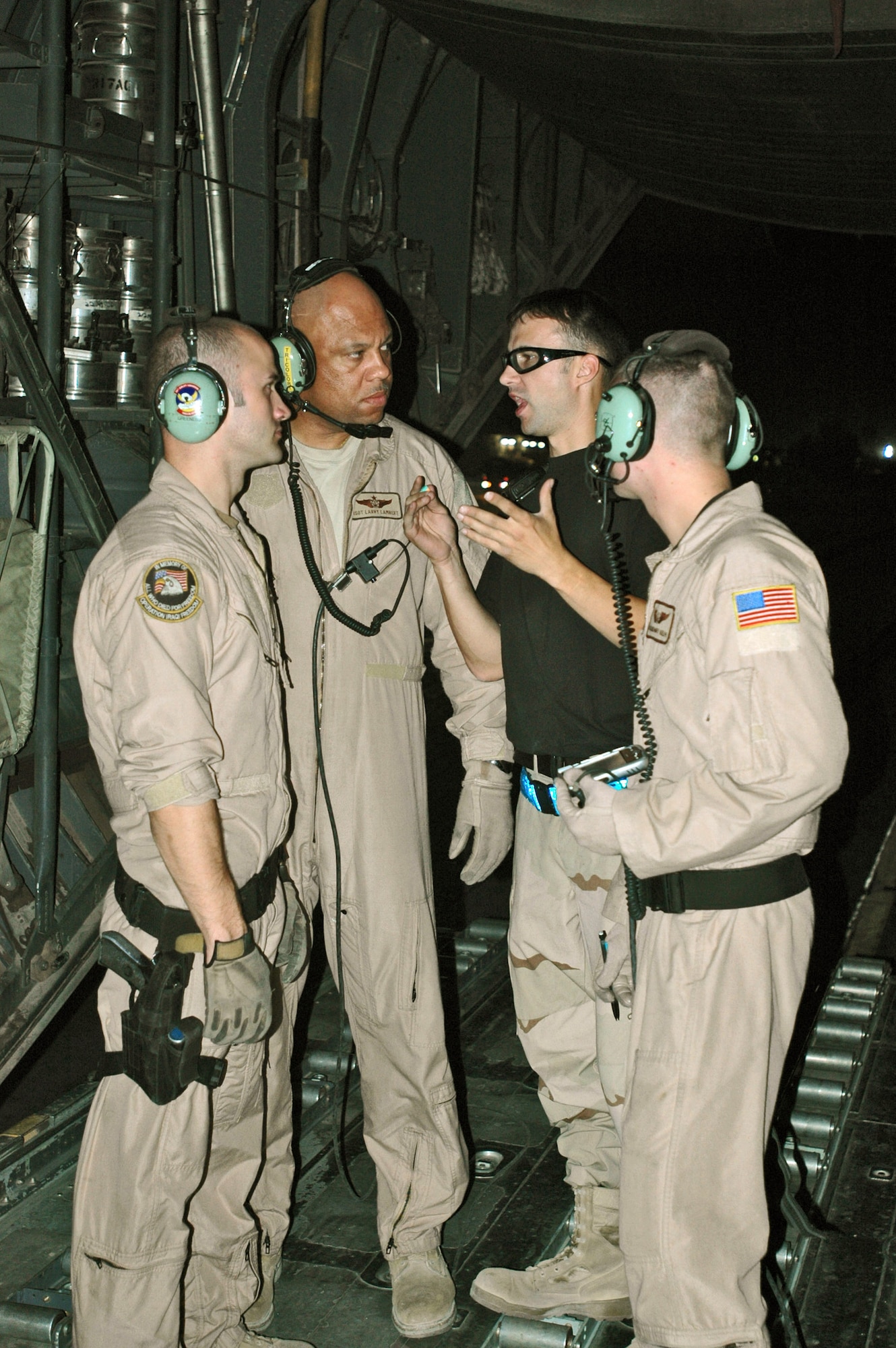 Staff Sgt. Tommy Greeness (left to right in flightsuits), Master Sgt. Larry Lambert and Airman 1st Class Zachary Kelhi are briefed by an Airman from the air terminal at Balad Air Base, Iraq, about the type of cargo they would be taking to Baghdad International Airport.  The three loadmasters from the 746th Expeditionary Airlift Squadron must configure the cargo area of their C-130 Hercules based on the size, amount and type of cargo to be carried.  (U.S. Air Force photo/Capt. Teresa Sullivan)