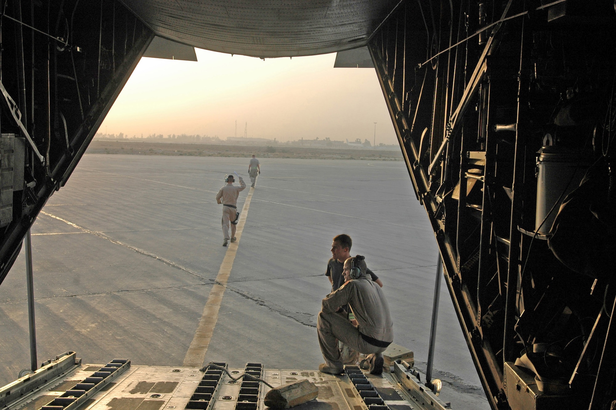Airman 1st Class Zachary Kelhi (kneeling) and Staff Sgt. Tommy Greeness watch the sun rise over Baghdad International Airport after a long night of delivering cargo and making airdrops over Iraq.  This was the last stop on their mission prior to flying back to the 379th Air Expeditionary Wing home base in Southwest Asia. (U.S. Air Force photo/Capt. Teresa Sullivan) 
