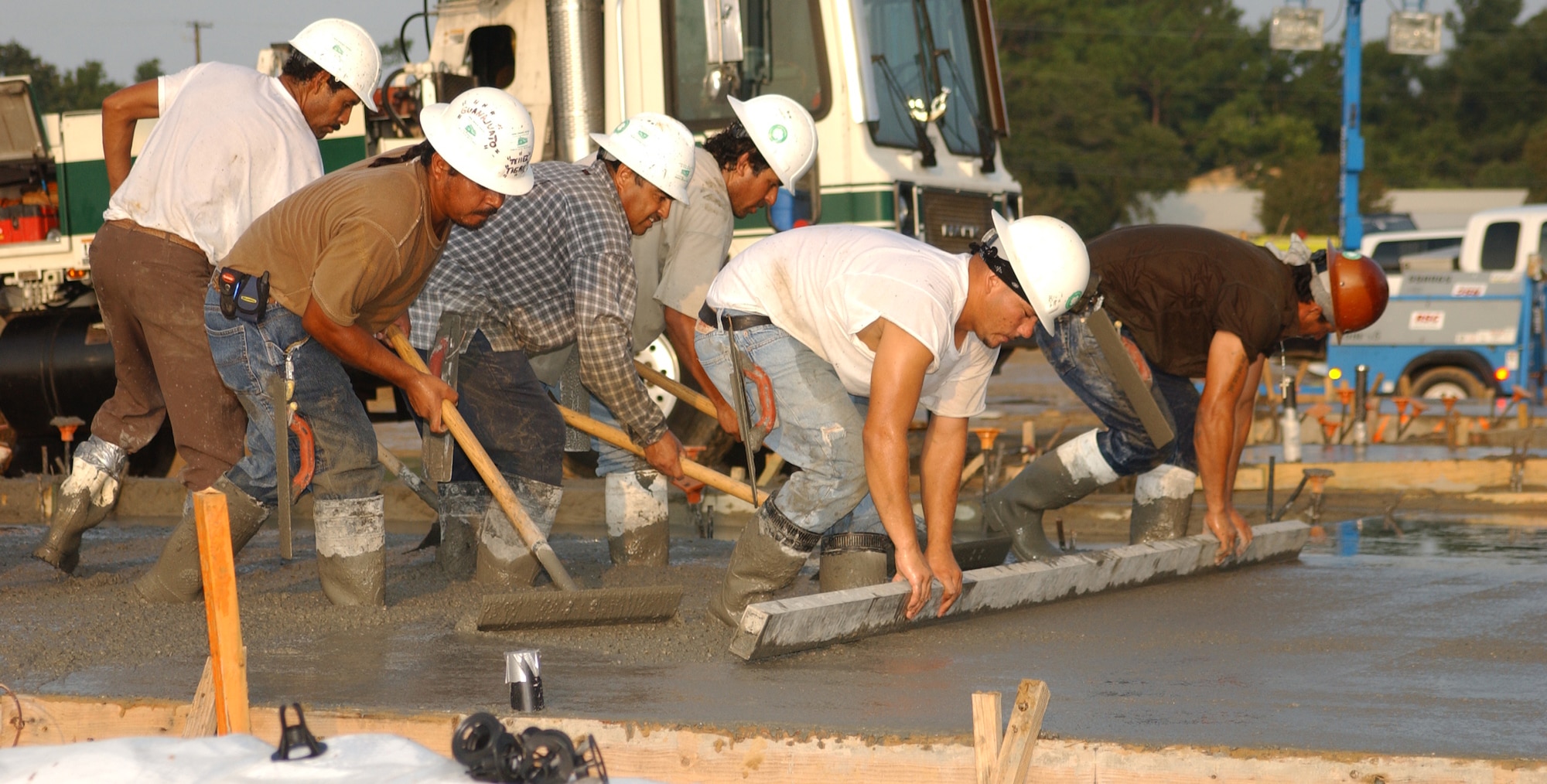 Workers for Hunt-Yates Construction team up to smooth the 30th out of 99 slabs to be poured for new duplexes in Thrower Park.  This work is done in the early morning hours so the concrete doesn’t dry while being poured in the summer heat.  (U.S. Air Force photo by Kemberly Groue)
