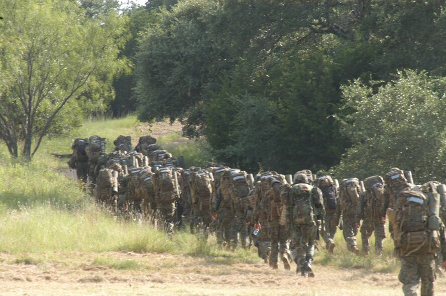 Marines and Airmen from Dyess Air Force Base, Texas, hump 60-lb. rucksacks for five miles at Camp Bowie, Texas, as part of their joint-service field training evolution Aug. 3. The Marine Reservists here, from Det-1, Motor Transportation Maintenance Co., do regular training and operational exercises and invited Airmen to join their experience. (U.S. Air Force photo by Senior Airman Carolyn Viss)