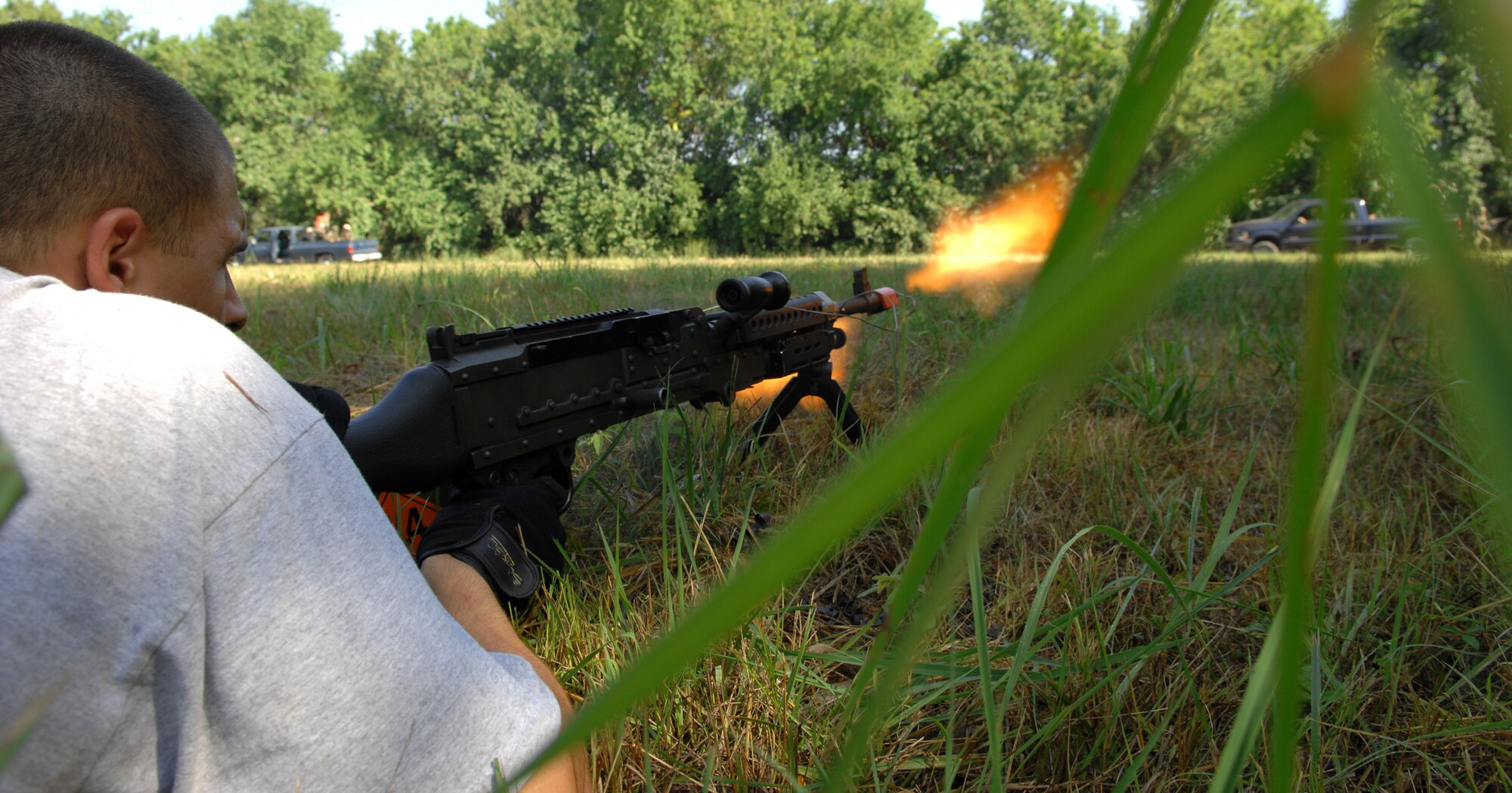 An insurgent acted out by Airman 1st Class Chance Farmer, 509th Security Forces Squadron, fires his M249 Squad Automatic Weapon at a convoy of Airmen at the Cobra Site during Air Expeditionary Combat Skills training Aug 10. (U.S. Air Force photo/Airman 1st Class Stephen Linch)