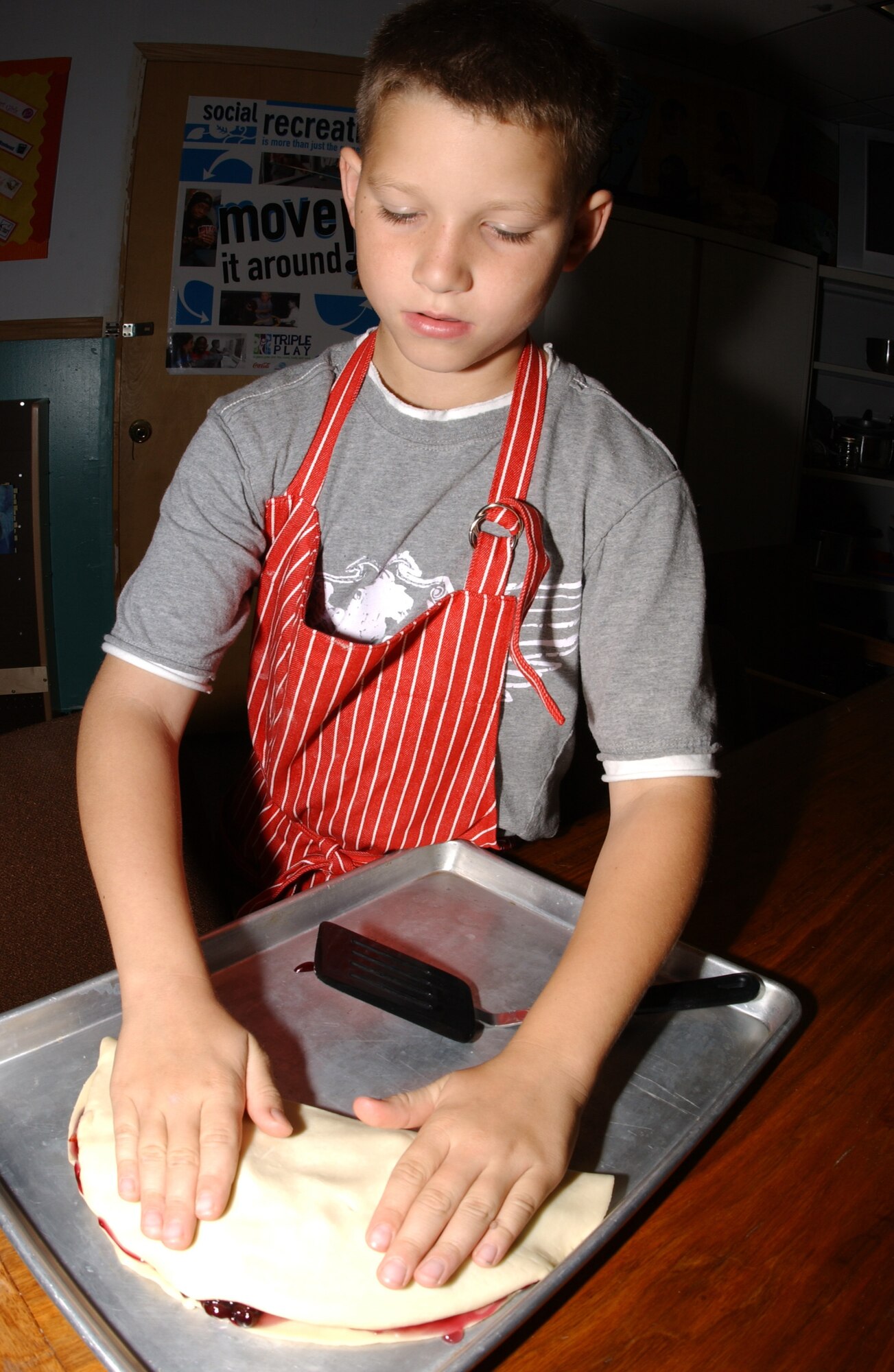 EIELSON AIR FORCE BASE, Alaska -- Kaleb Albert, son of Heather and Staff Sgt. Matthew Albert, 354th Contracting Squadron, folds over the pastry desert to place in the oven August 14 at the Youth Center. The Youth Center is conducting a six-week cooking program for children aged 9-12 to teach them the importance of eating healthy and experimenting with different tastes.  (U.S. Air Force Photo by Airman 1st Class Jonathan Snyder)(Released)