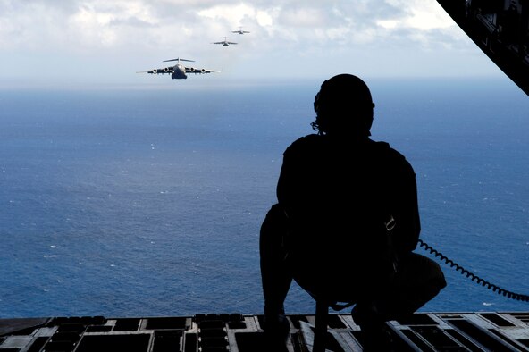 Senior Airman Todd Tichawa watches a formation of C-17 Globemaster III's from the back of his aircraft during a four-ship, airdrop training mission Aug. 13 over the island of Oahu, Hawaii. Airman Tichawa, a loadmaster with the 535th Airlift Squadron from Hickam Air Force Base, Hawaii, is taking part in the training to maintain currency and proficiency. (U.S. Air Force photo/Tech. Sgt. Shane A. Cuomo) 
