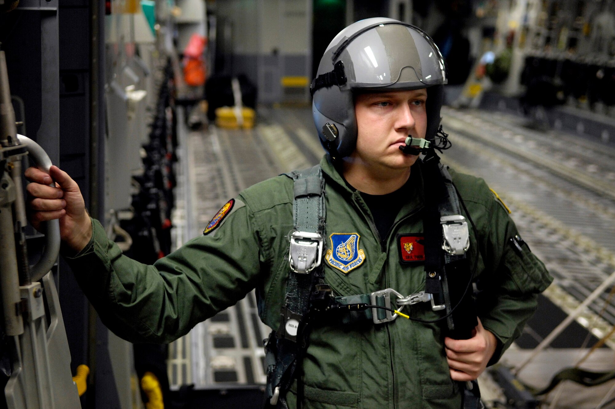 Senior Airman Todd Tichawa waits to open the ramp door to a C-17 Globemaster III during a four-ship, airdrop training mission Aug. 13 over the island of Oahu, Hawaii. Airman Tichawa, a loadmaster with the 535th Airlift Squadron from Hickam Air Force Base, Hawaii, is taking part in the training to maintain currency and proficiency. (U.S. Air Force photo/Tech. Sgt. Shane A. Cuomo) 
