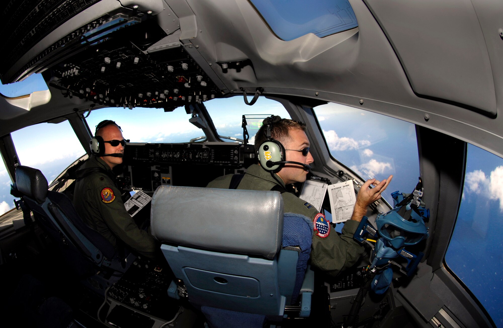 Maj. Matt Zehr and Capt. Rocky Harvey check the positions of other C-17 Globemaster IIIs during a four-ship, airdrop training mission Aug. 13 over the island of Oahu, Hawaii. The Airmen, pilots from the 535th Airlift Squadron from Hickam Air Force Base, Hawaii, are conducting the training to maintain currency and proficiency. (U.S. Air Force photo/Tech. Sgt. Shane A. Cuomo)
