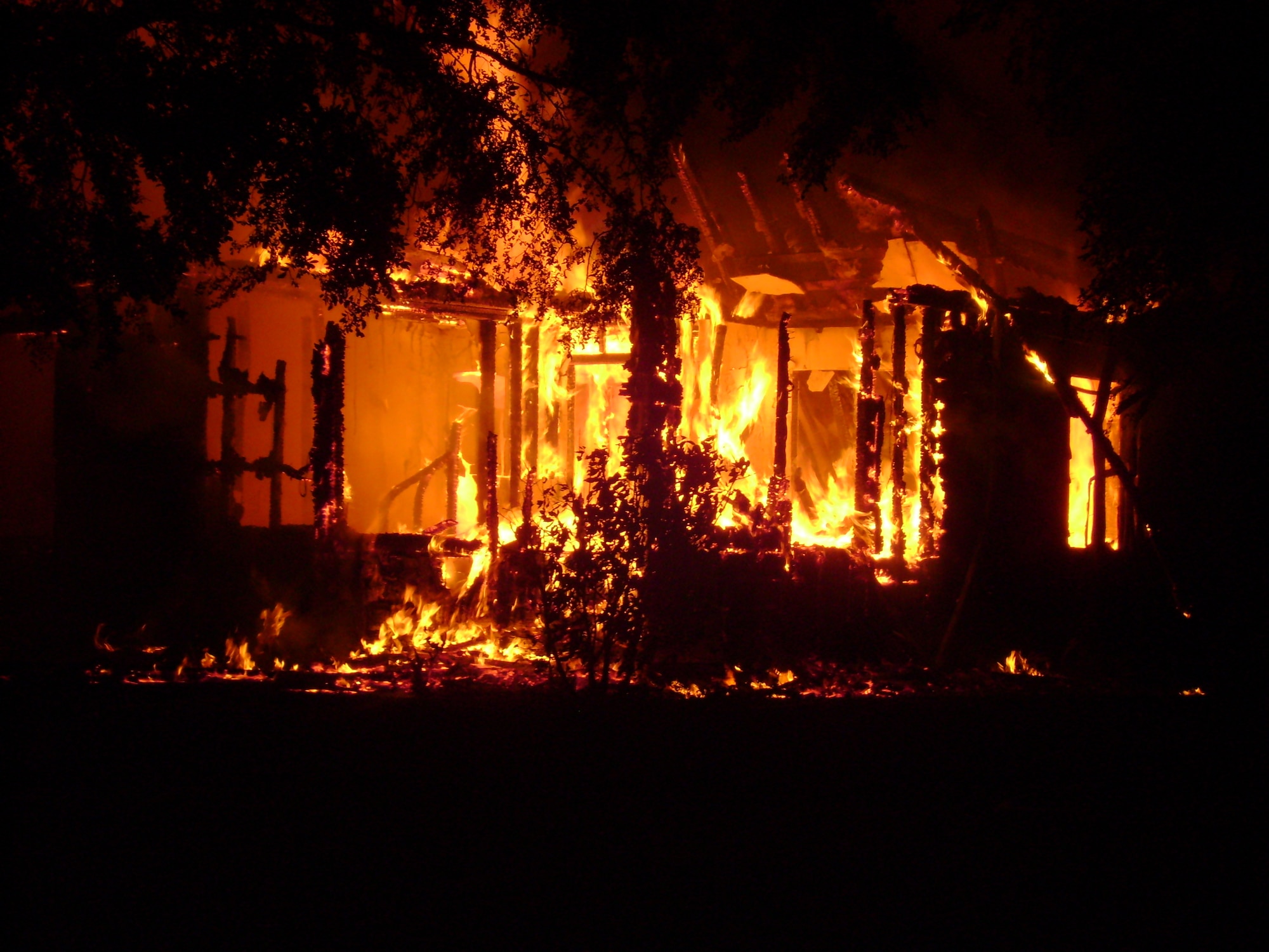 The infrastructure of a home in Wherry Housing crumbles under a fiery onslaught Aug. 14.  No one was inside the house, and none of the responders were injured.  (U.S. Air Force photo)                            