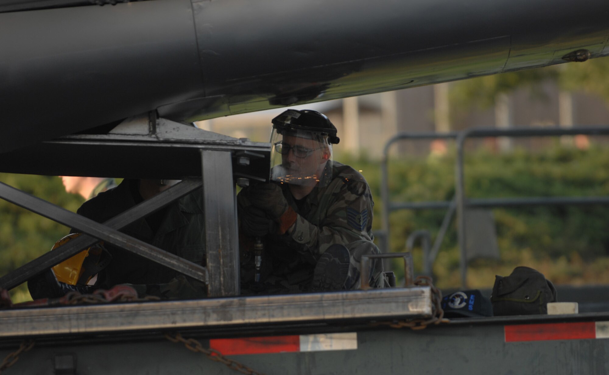 Tech. Sgt. Larry Moshier, 48th Equipment Maintenance Squadron at RAF Lakenheath, grinds the welds off of the stand of the newly renovated display F-100 was on during its recent reconstruction. (U.S. Air Force photo by Airman 1st Class Jessica Snow)