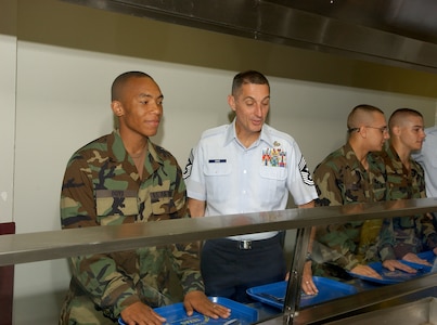 Maintaining military discipline while going through the breakfast line with Chief Master Sgt. Jonathan Hake and other command chief master sergeants, basic trainees in the 324th Training Squadron listen to and offer comments on the Air Force and their training. Chief Hake is the command chief master sergeant for Air Force Materiel Command. He, along with other command chiefs, and Chief Master Sergeant of the Air Force Rodney McKinley, were on Lackland AFB, Texas, from Aug. 8 through Aug. 10 for the triennial review of basic military training. (USAF photo by Alan Boedeker)                              