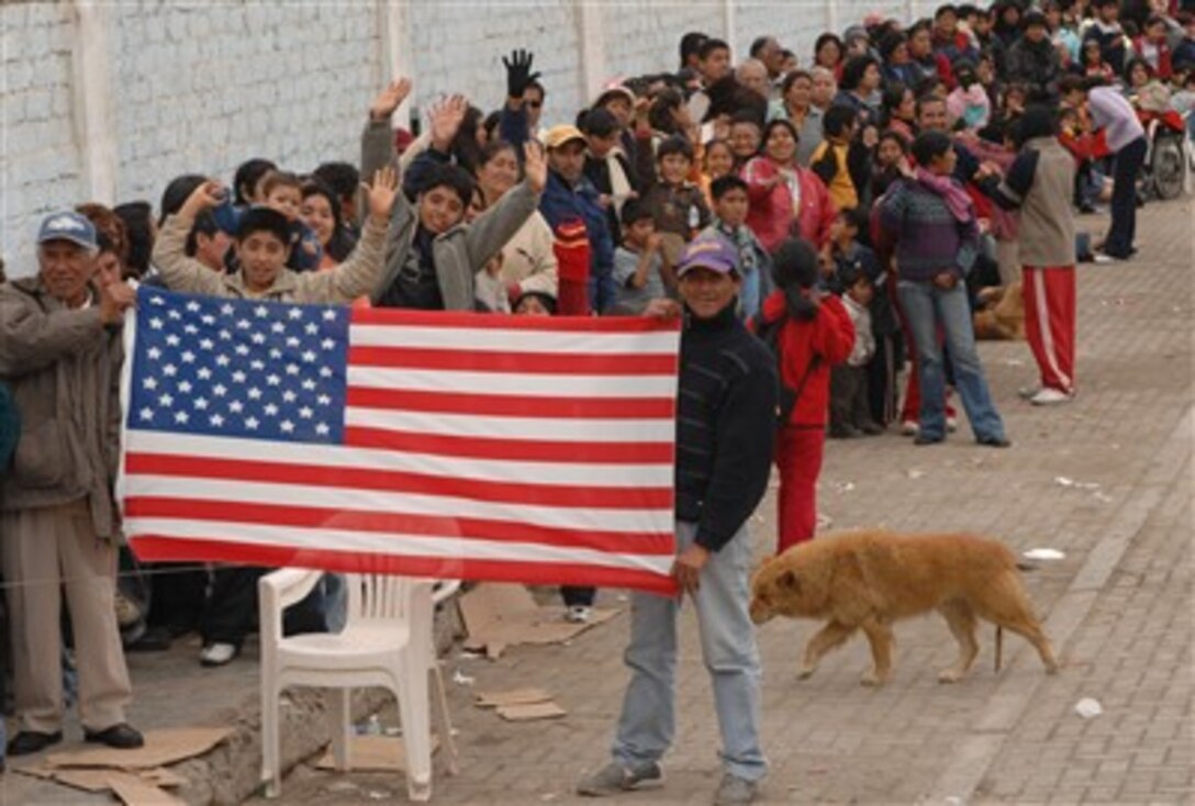 Peruvians display an American flag while waiting in line for medical care at Miguel Grau School in Salaverry, Peru, Aug. 10. The hospital ship USNS Comfort  provided dental, optometry, pediatrics and adult medicine services.