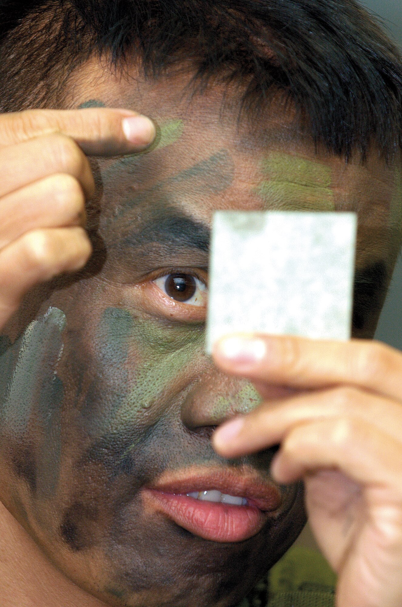 Staff Sgt. Jerry Dean, 349th Communications Squadron, Travis AFB, Calif., uses a small mirror to apply camouflage during the three-week Combat Readiness School at Tinker AFB, Okla. (Air Force photo by Margo Wright)    