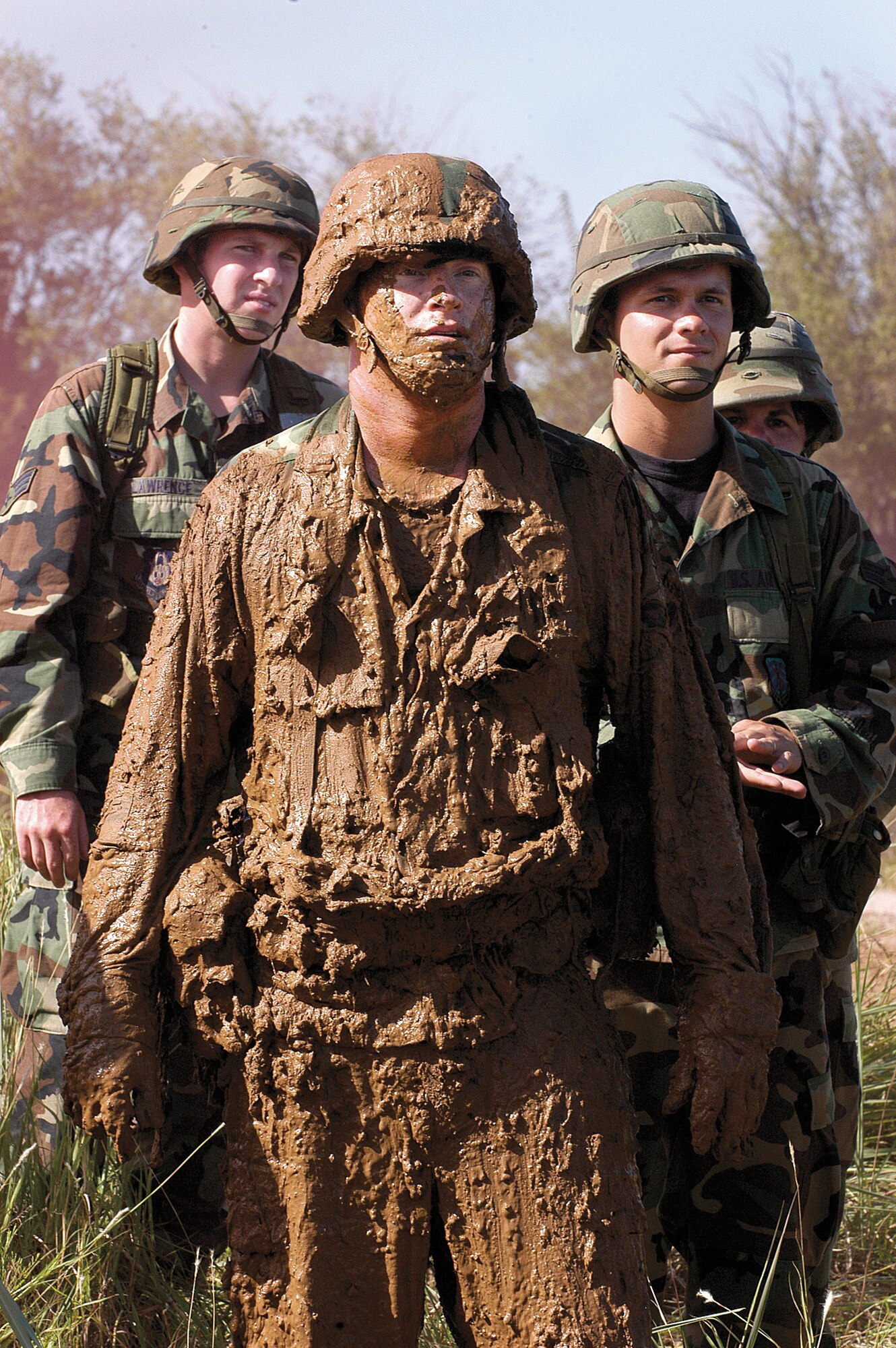 After practicing low and high crawl techniques through a mud pit in the Glenwood Training Area at Tinker AFB, Okla., Senior Airman Jason Decker, 35th Combat Communications Squadron, catches his breath and watches the next team. Senior Airman Paul Lawrence, left, 349th Communications Squadron, Travis AFB, Calif. and Airman 1st Class Samuel Newhouse, 32nd CCS, Tinker, wait their turn. (Air Force photo by Margo Wright) 