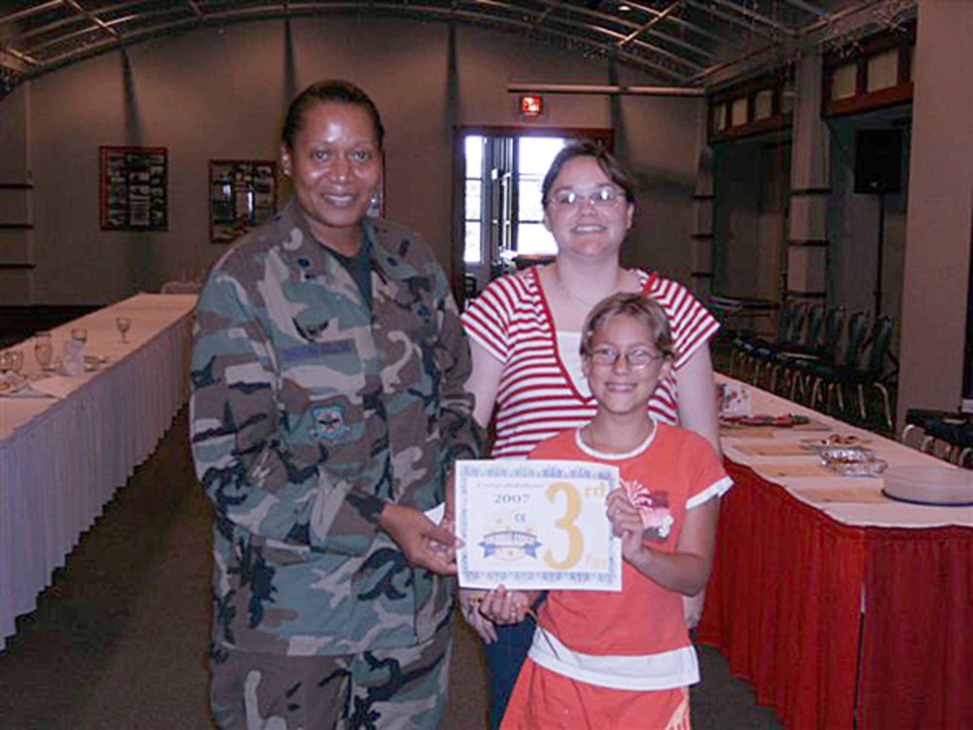 MCCONNELL AIR FORCE BASE, Kan. – Lt. Col. Sonya Collins, 22nd Services Squadron commander presents a third place certificate to Aislynn Richey, 12, and her mother Rena, McConnell family members, for her cookies entered in the Colossal Cookie Challenge, Aug. 9 at the Robert J. Dole Center. The contest was hosted by the 22nd Services Squadron and had 18 entries. Contestants’ entries were judged on taste, appearance and creativity. (photo by Amanda Pozehl) 