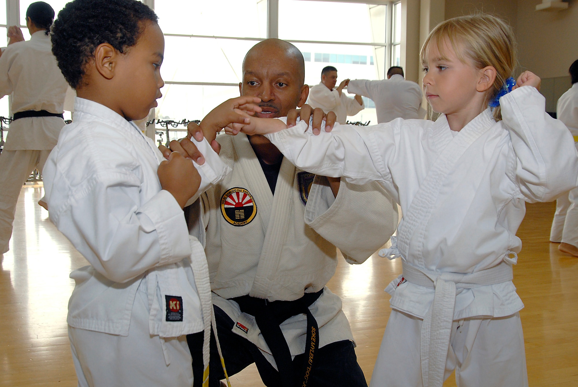 Alonzo M. Jones instructs Quentin Evans, 4, and Avianna Raupach, 6, in the Cory Jitsu / Comba-tai discipline. Martial Arts students and fans gathered at the Los Angeles AFB Fitness Center for a demo, Aug. 11.  (Photo by Joe Juarez)