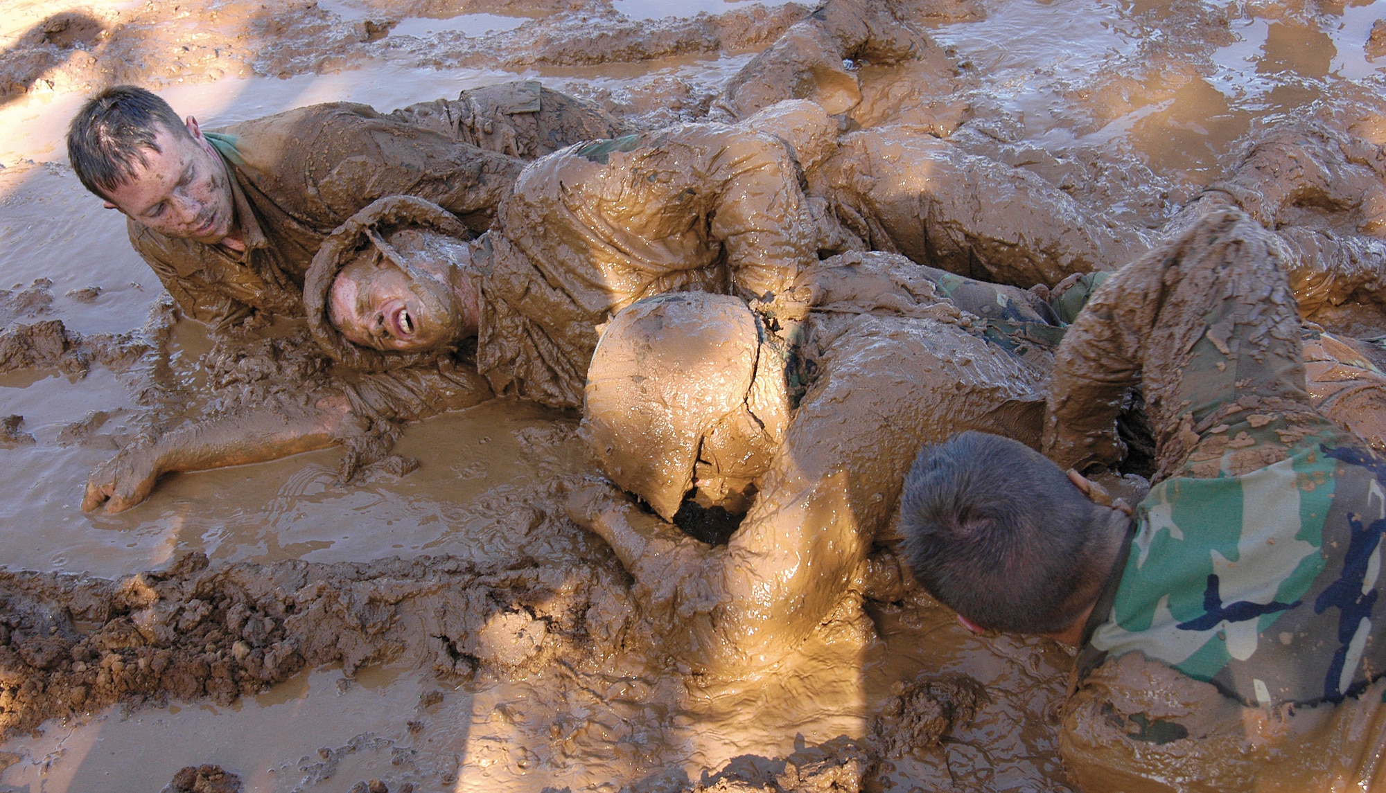 Airmen strain to move inches through mud, perfecting low- and high-crawl techniques during week one of the Combat Readiness School at Tinker AFB, Okla.  Instructors drill into students the motto of “no one left behind” and watch the concept take hold as Airmen enter the pit as individuals, but struggle to the end as a team, encouraging and pulling each other to the finish. Fire team members from left are; Staff Sgt. Rich Brumbaugh, 349th Communications Squadron, Travis AFB, Calif; Staff Sgt. Christopher Kelley, 33rd Combat Communications Squadron, Tinker; Senior Airman Raid Alawar, 349th CS; and Airman Micheal Garner, 31st CCS, Tinker. (Air Force photo by Margo Wright)   