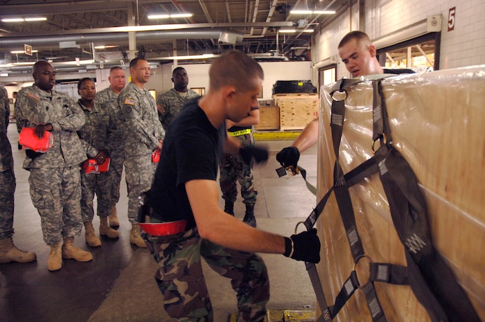 Army Soldiers from the 403rd Transportation Battalion in Anastien, Ala., watch 437th Aerial Port Squadron Airmen properly secure the netting to a pallet prior to it being shipped out to it's location Monday.(U.S. Air Force Photo/Staff Sgt. April Quintanilla)