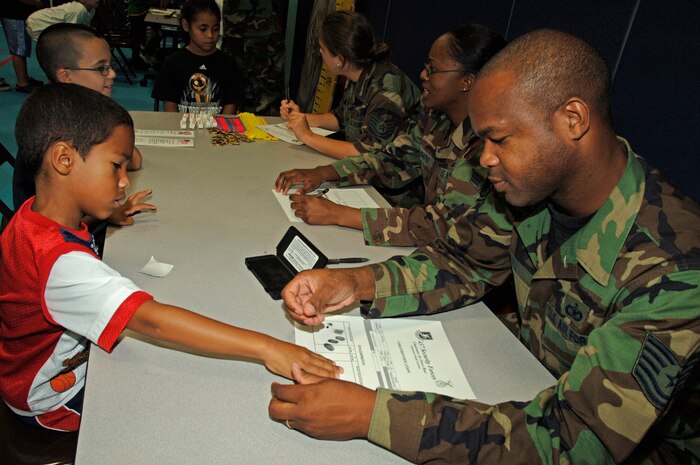Tech. Sgt. Jermaine Gibbs, 437th Security Forces Delta Flight sergeant, takes the finger prints of Eli Gravely, 6, son of Dana Gravely, at Charleston's Youth Program Center Thursday. (U.S. Air Force Photo/Staff Sgt. April Quintanilla)