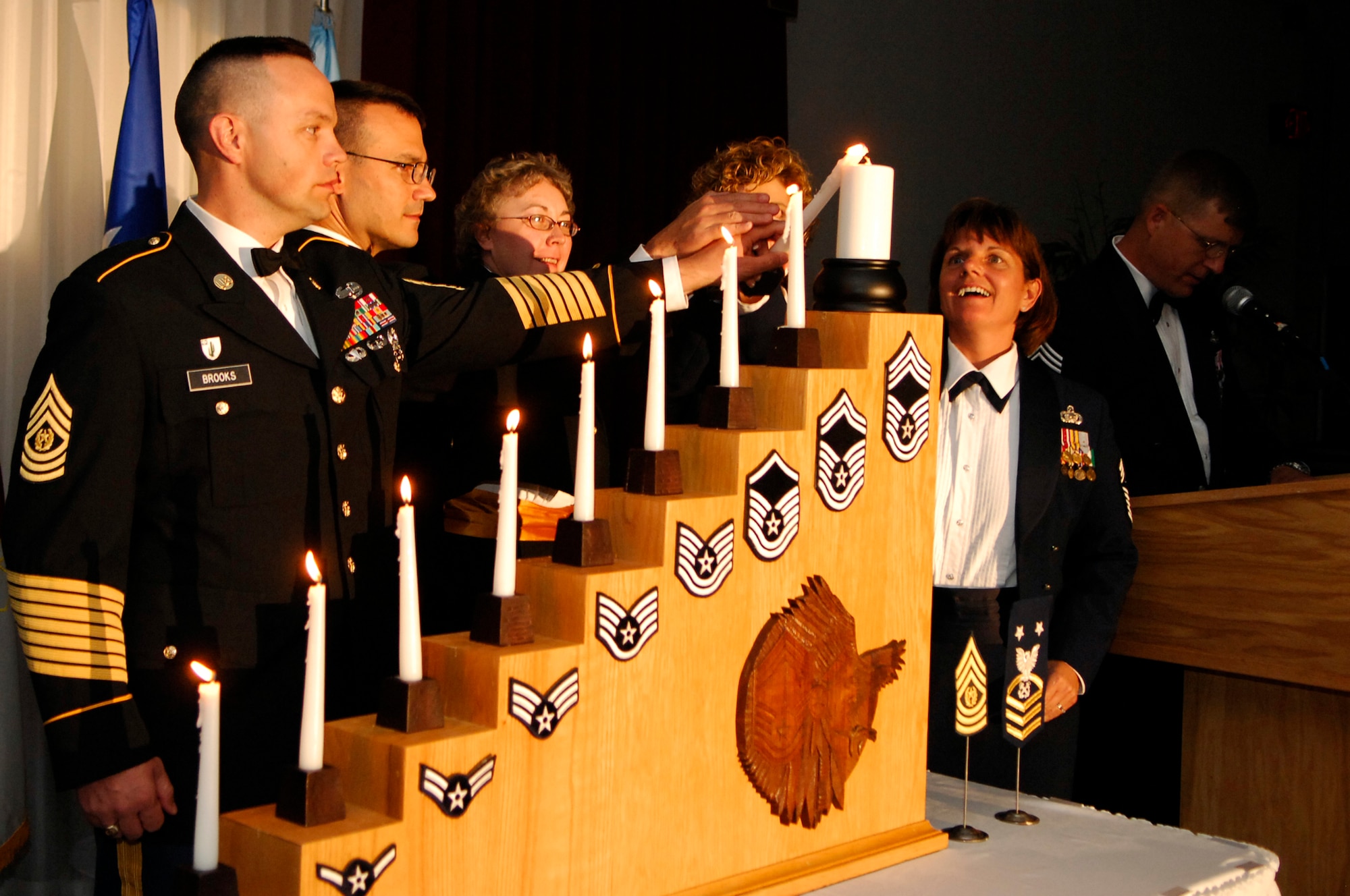 HANSCOM AFB, Mass. -- From left, Army Command Sgt. Maj. Peter Brooks, garrison command sergeant major, Fort Devens, Mass.; Coast Guard Master Chief Petty Officer Sean McPhilamy, command master chief for U.S. Coast Guard Sector Boston; Coast Guard Master Chief Petty Officer Nadine Gookin, property adviser for U.S. Coast Guard Electronic Systems Support Unit Boston; Senior Master Sgt. Ginger Thompson, 66th Medical Group superintendent, and Chief Master Sgt. Lisa Sirois, Electronic Systems Center and 66th Air Base Wing command chief master sergeant, light a candle representing the E-9 grade during the Chief’s Recognition Ceremony Aug. 10 in the Minuteman Club ballroom. (U.S. Air Force photo by Mark Wyatt
